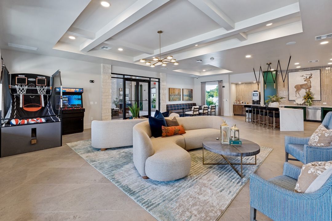 Modern hotel lobby with white seating, blue accents, and a bar area under recessed ceiling lights