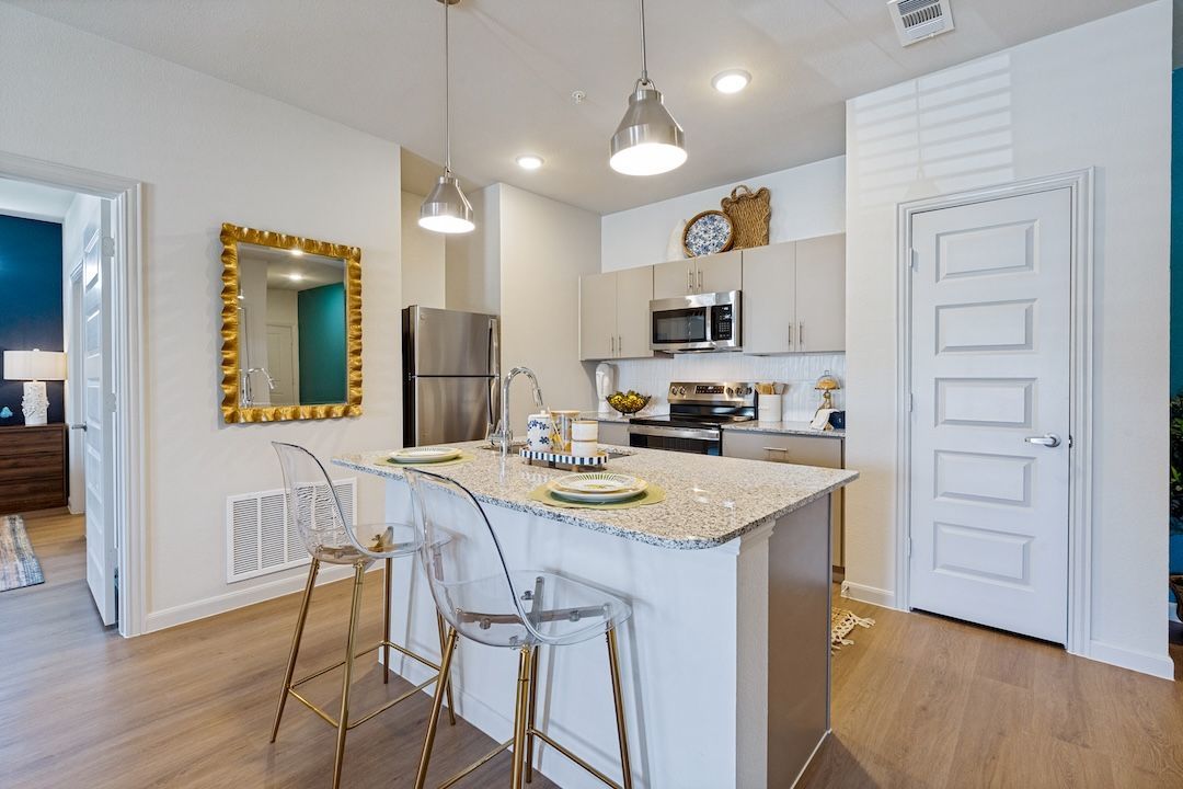 Modern kitchen with white cabinets, granite island, bar stools, and pendant lights