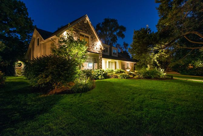 A house is lit up at night with lots of lights on the lawn.