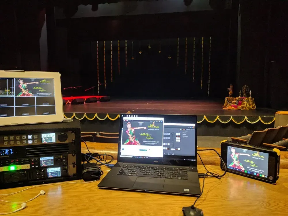 Stage control setup with multiple screens and audio equipment facing an empty stage