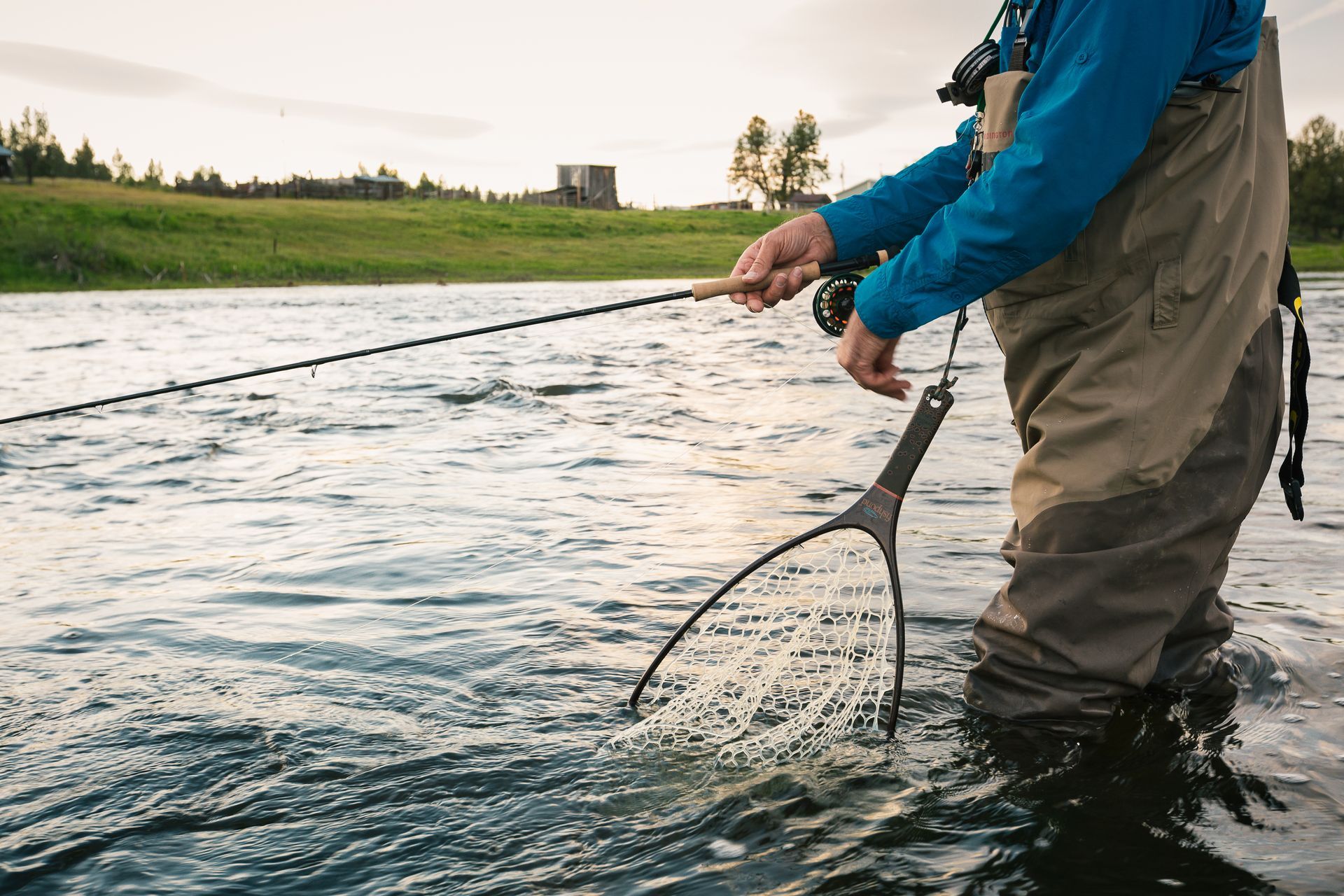 somebody holding a fishing line out by a lake.