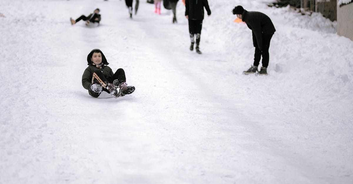 A group of people are sledding down a snow covered road.