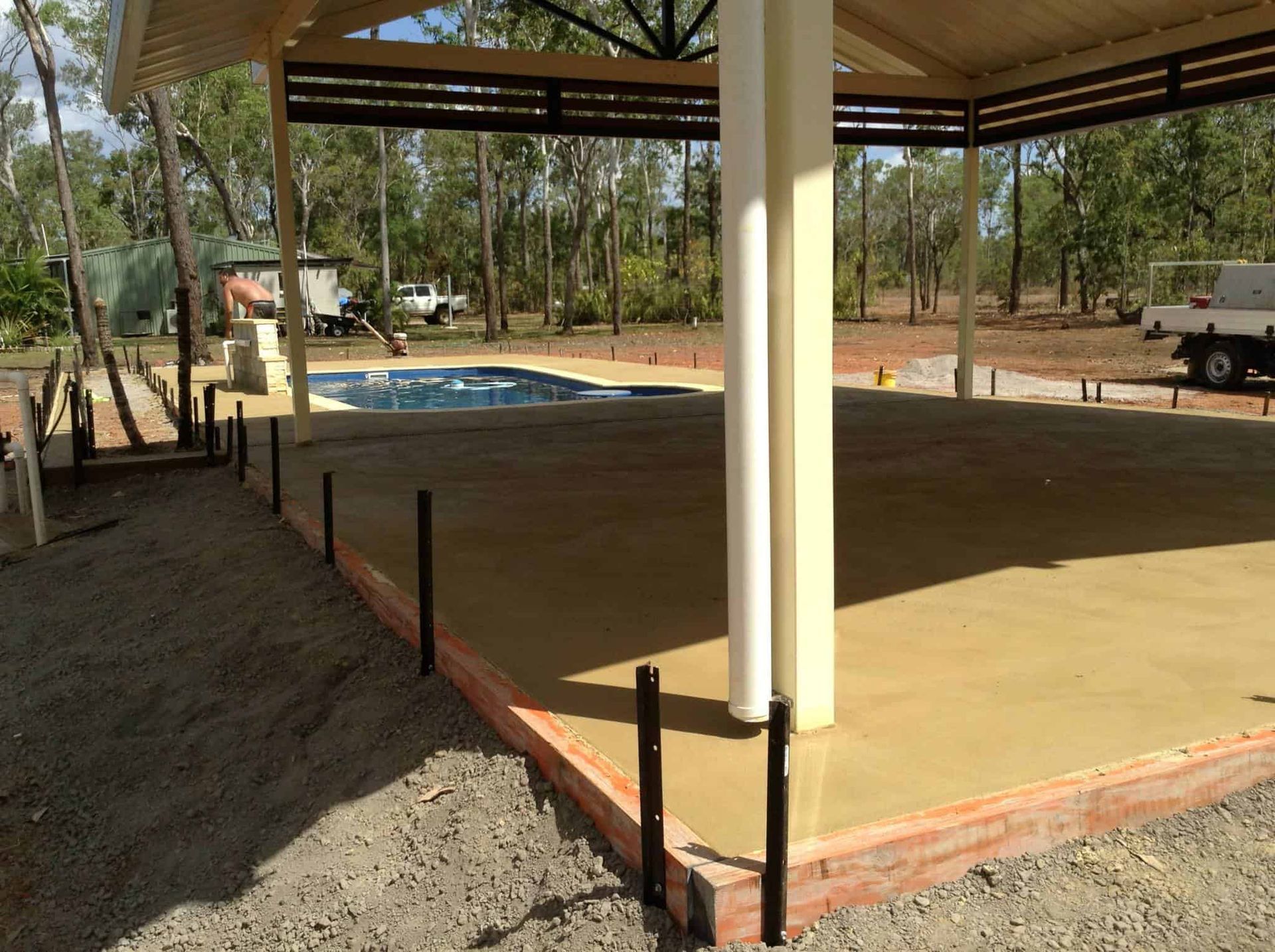 Concrete slab with a gazebo, near a swimming pool and trees. Construction site.