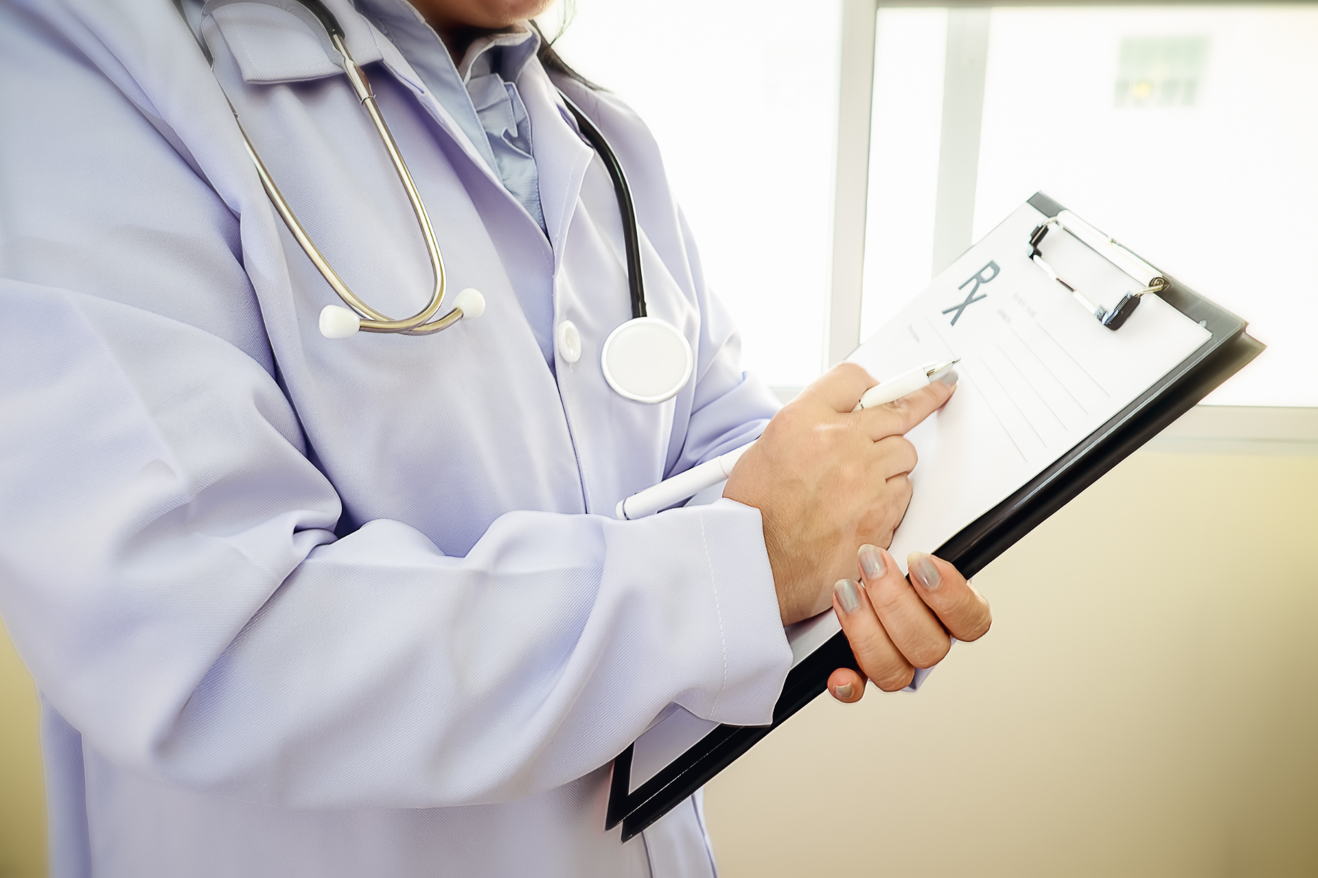 A doctor is holding a clipboard and pointing at it.