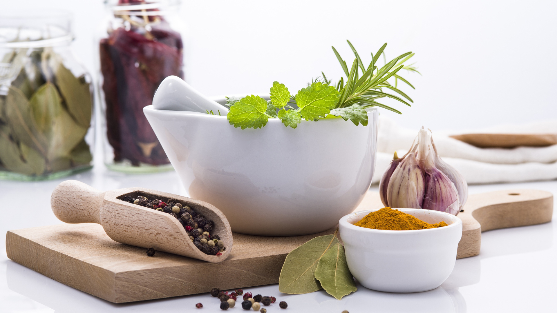 Garlic bulbs, peppercorns, cinnamon sticks, and spices arranged on a rustic wooden surface.