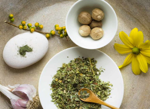 A wooden spoon is in a bowl of dried herbs.