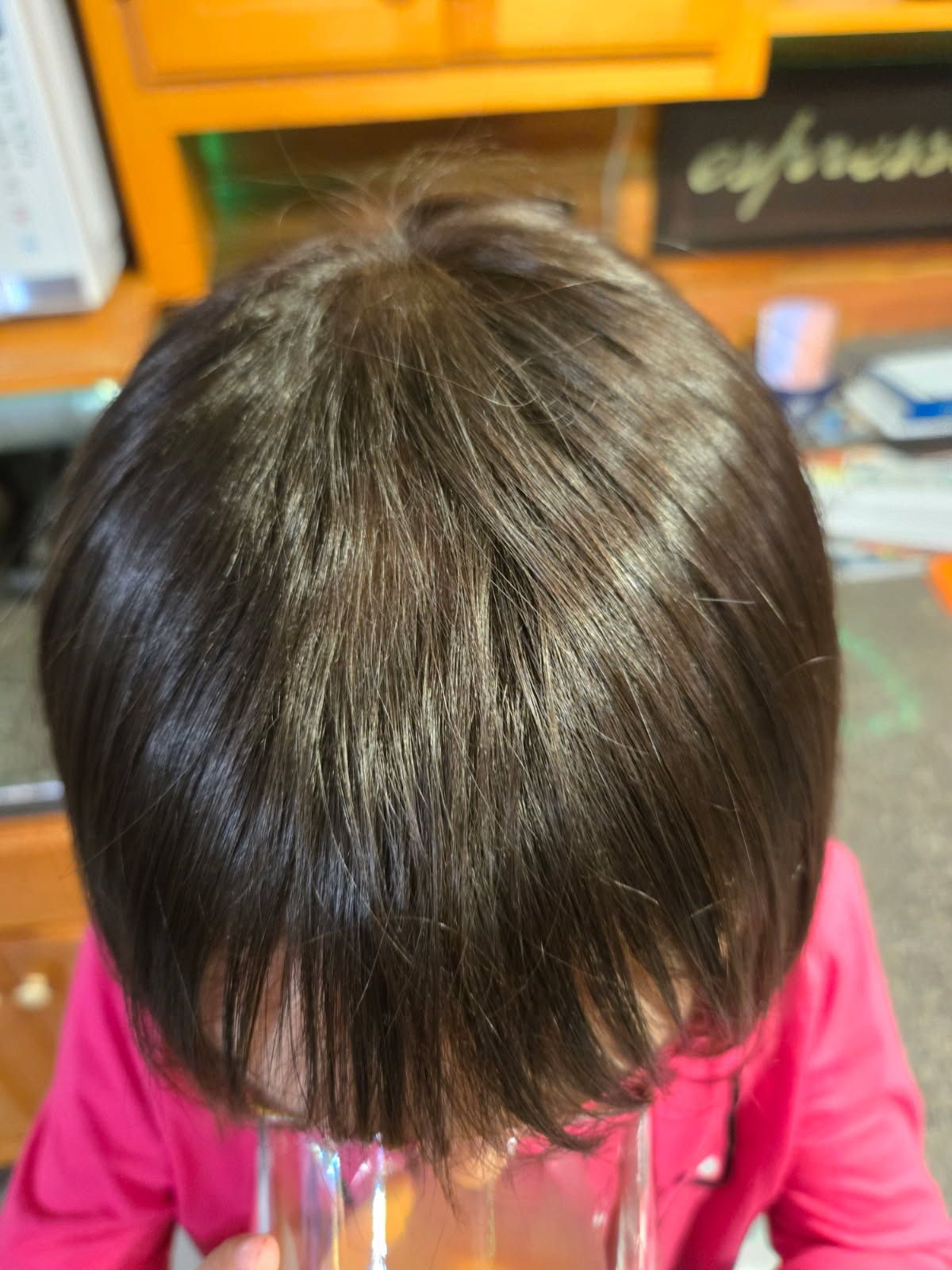 A close up of a child 's hair with a pink shirt on.