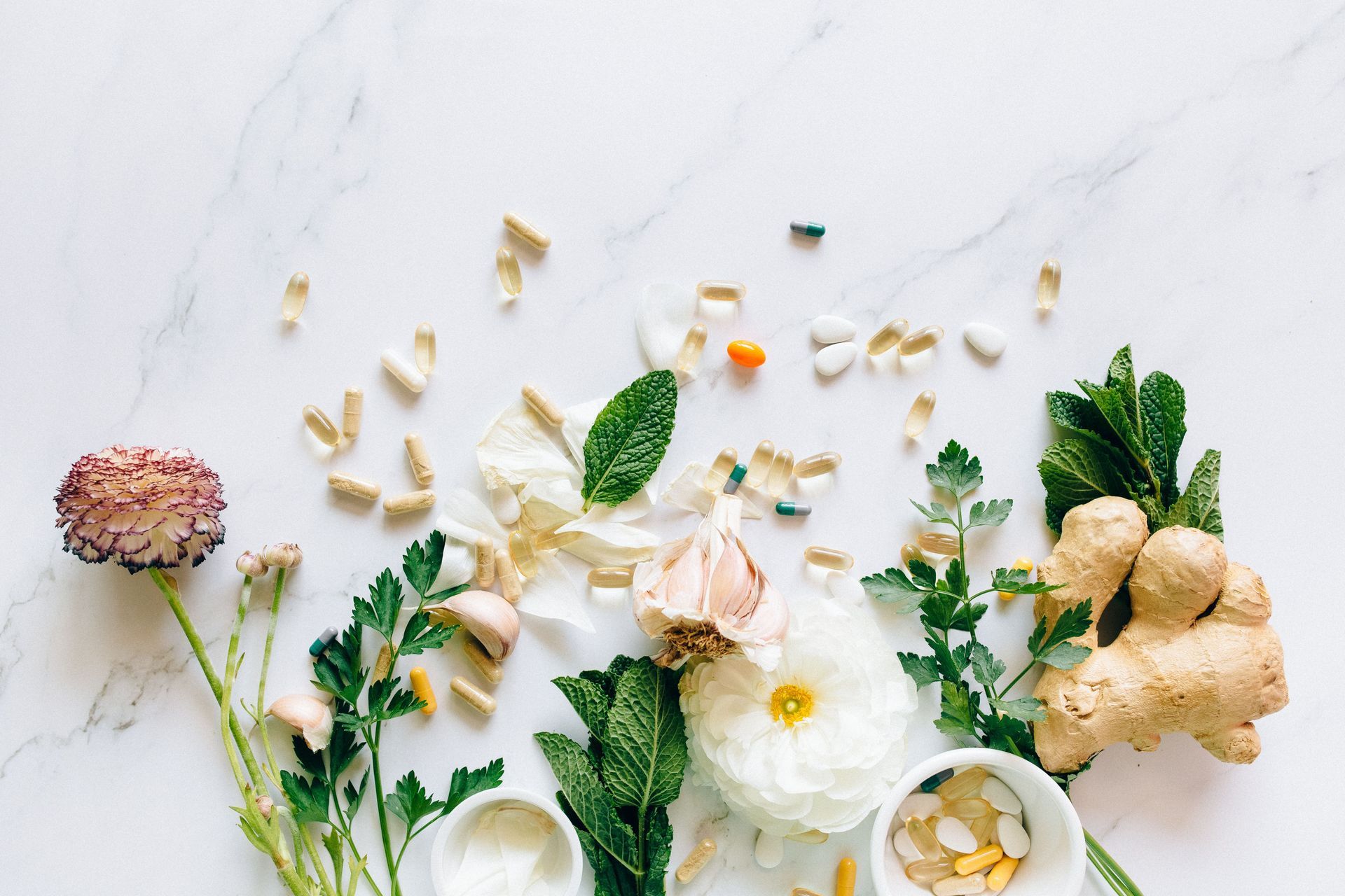 A stethoscope , mortar and pestle , pills , and herbs are on a table.