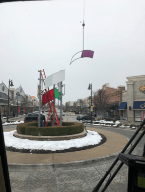 Roundabout with flags being installed at a shopping center on a cloudy day.