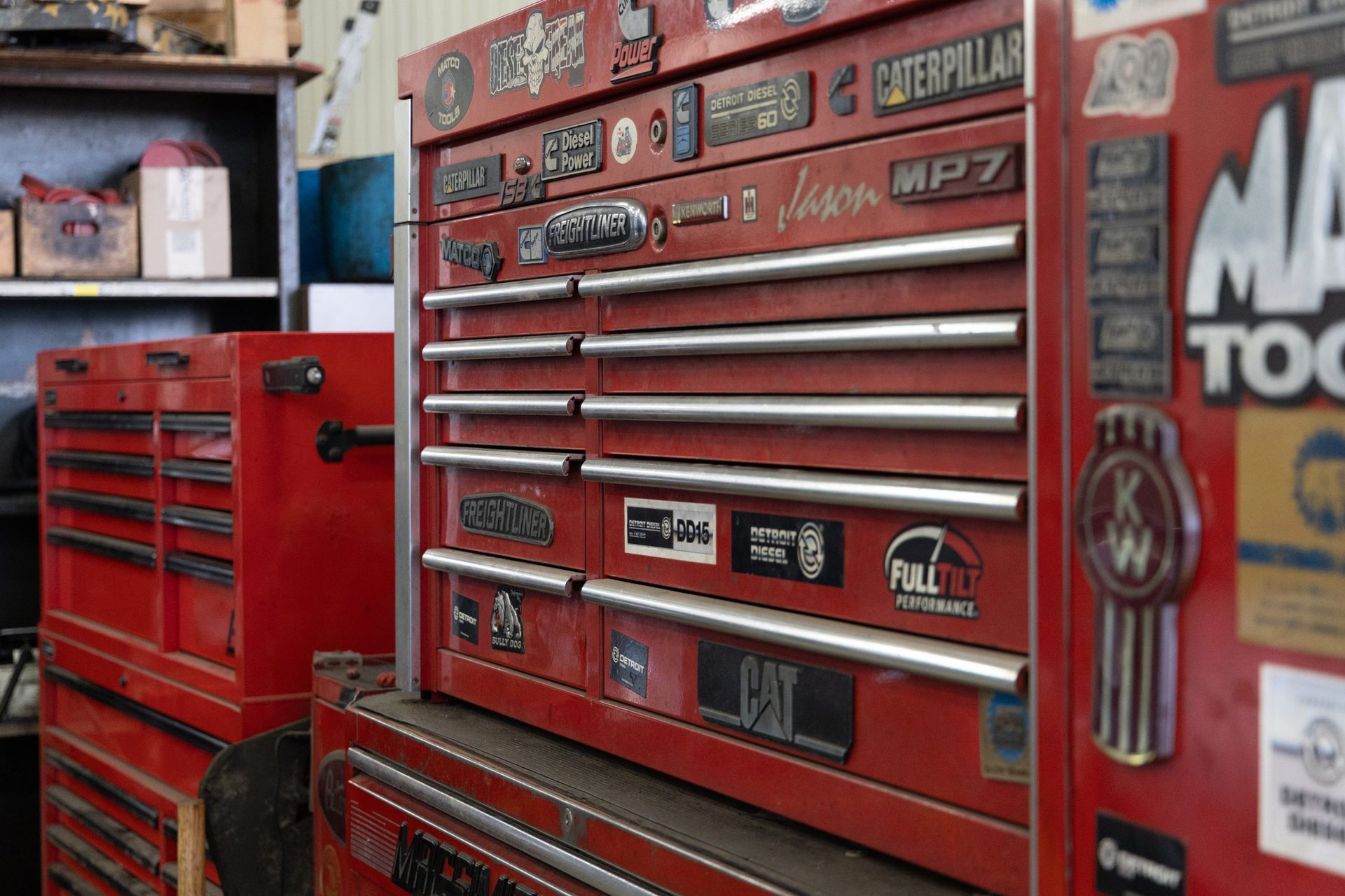 Red tool chests covered in stickers in a garage. One has 