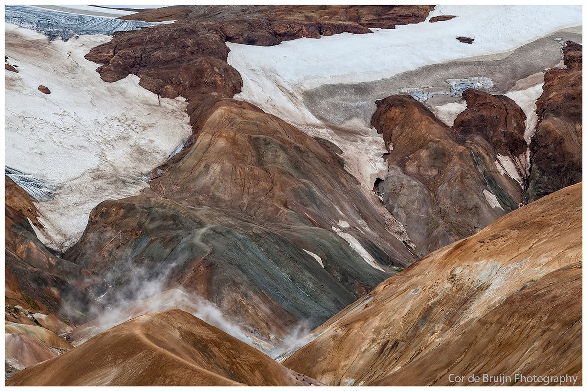 Colorful mountain landscape with snow patches and smoky haze.
