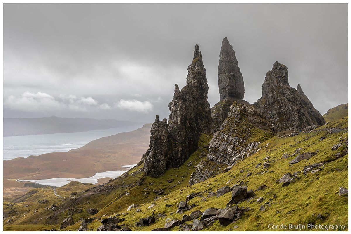 Jagged rock formations on a grassy hillside in Scotland, overlooking a misty sea.
