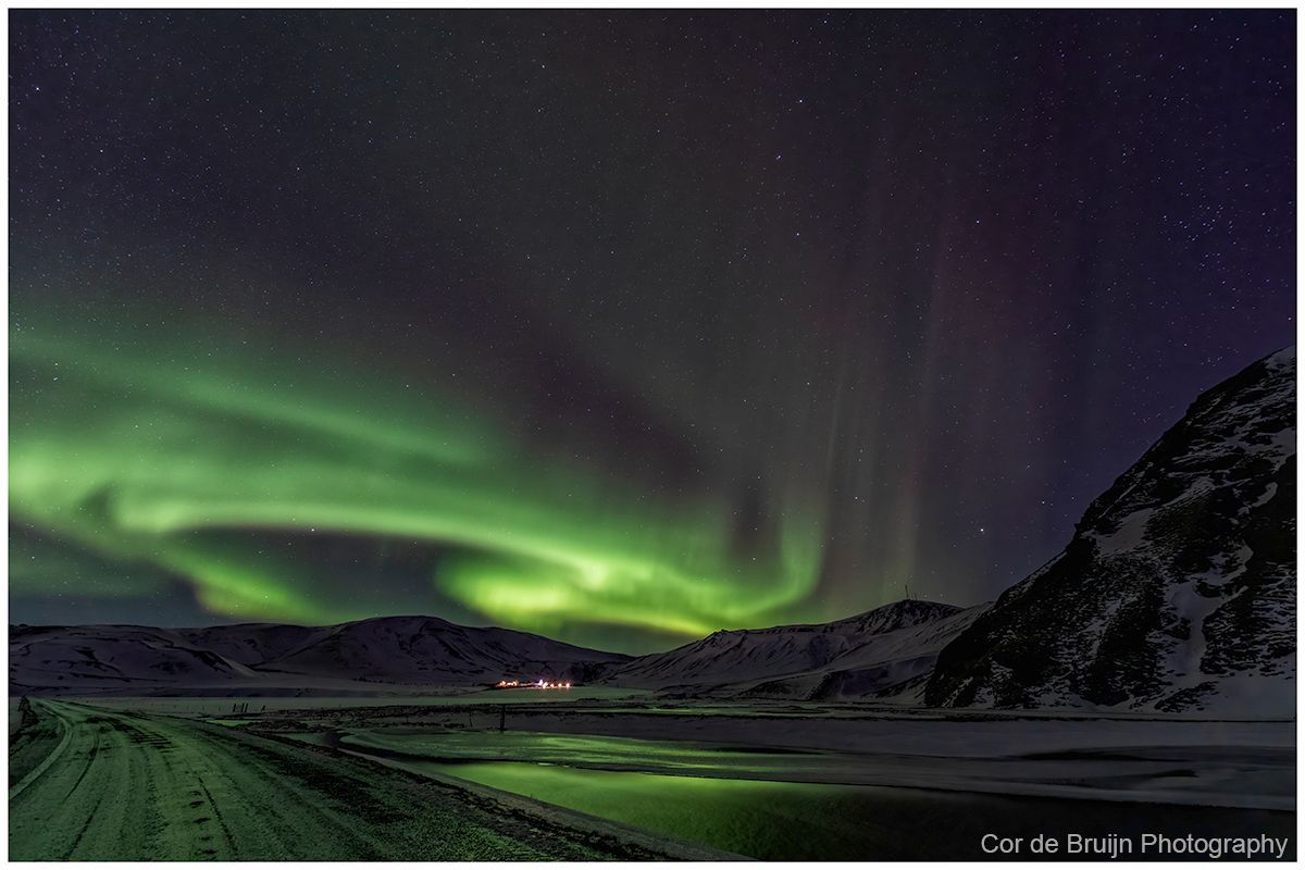 Green aurora over snowy mountains and a dark valley at night