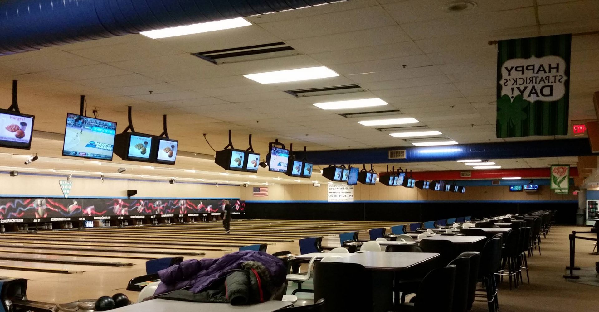 Wide interior shot of Scores Fun Center &mdash; rows of polished wood bowling lanes under fluorescent lighting