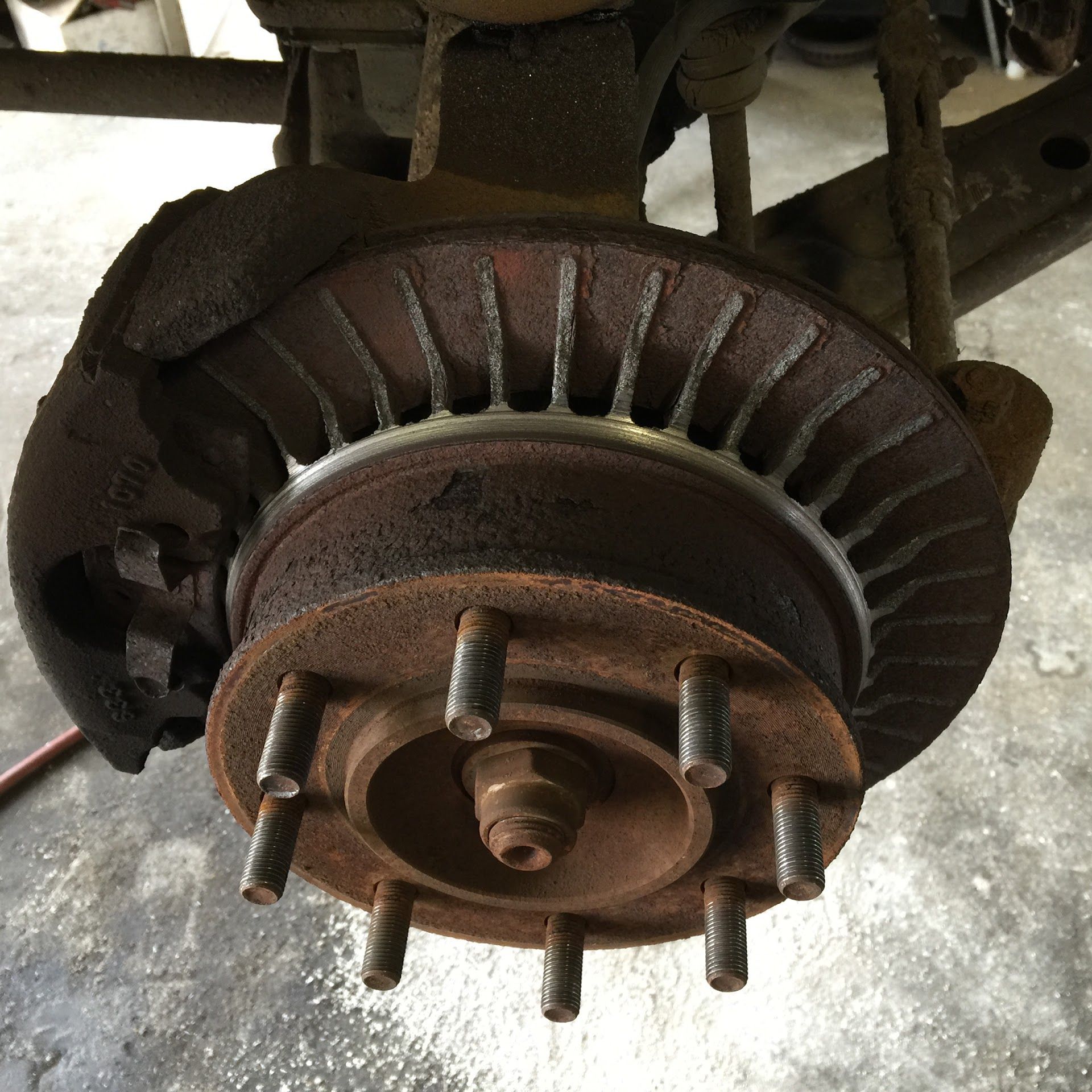 Rusty car brake rotor with caliper and lug studs | South Beach Towing & Repair
