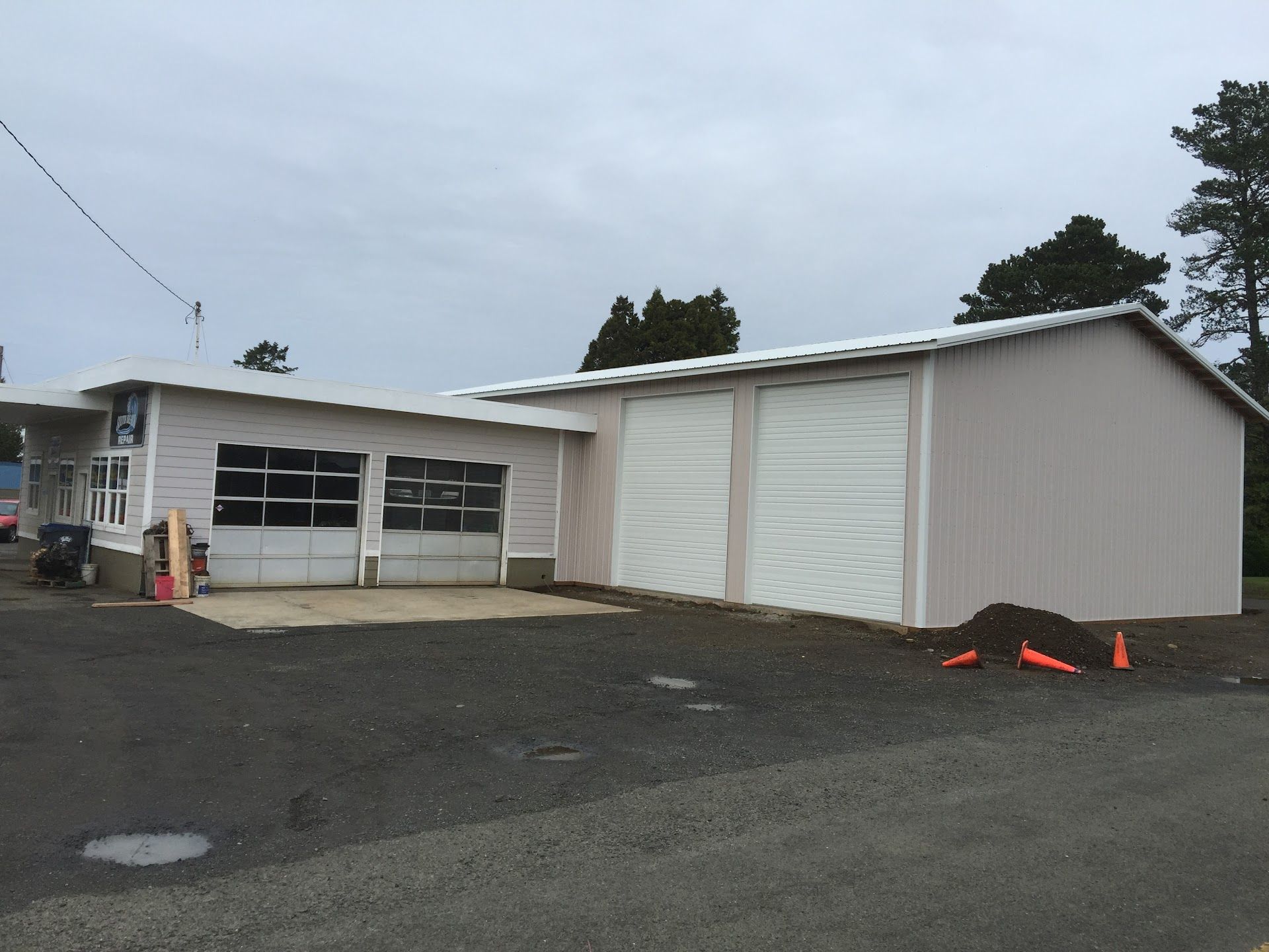A light pink auto repair shop building with two garage bays, under a cloudy sky | South Beach Towing & Repair