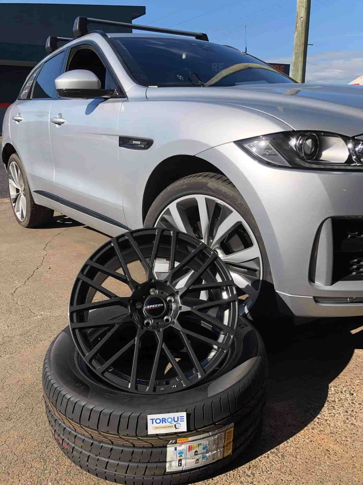 A Silver Car Next to A Stack of Tires and Wheels — Torque Tyres & Trailer Spares Cairns in Cairns, QLD
