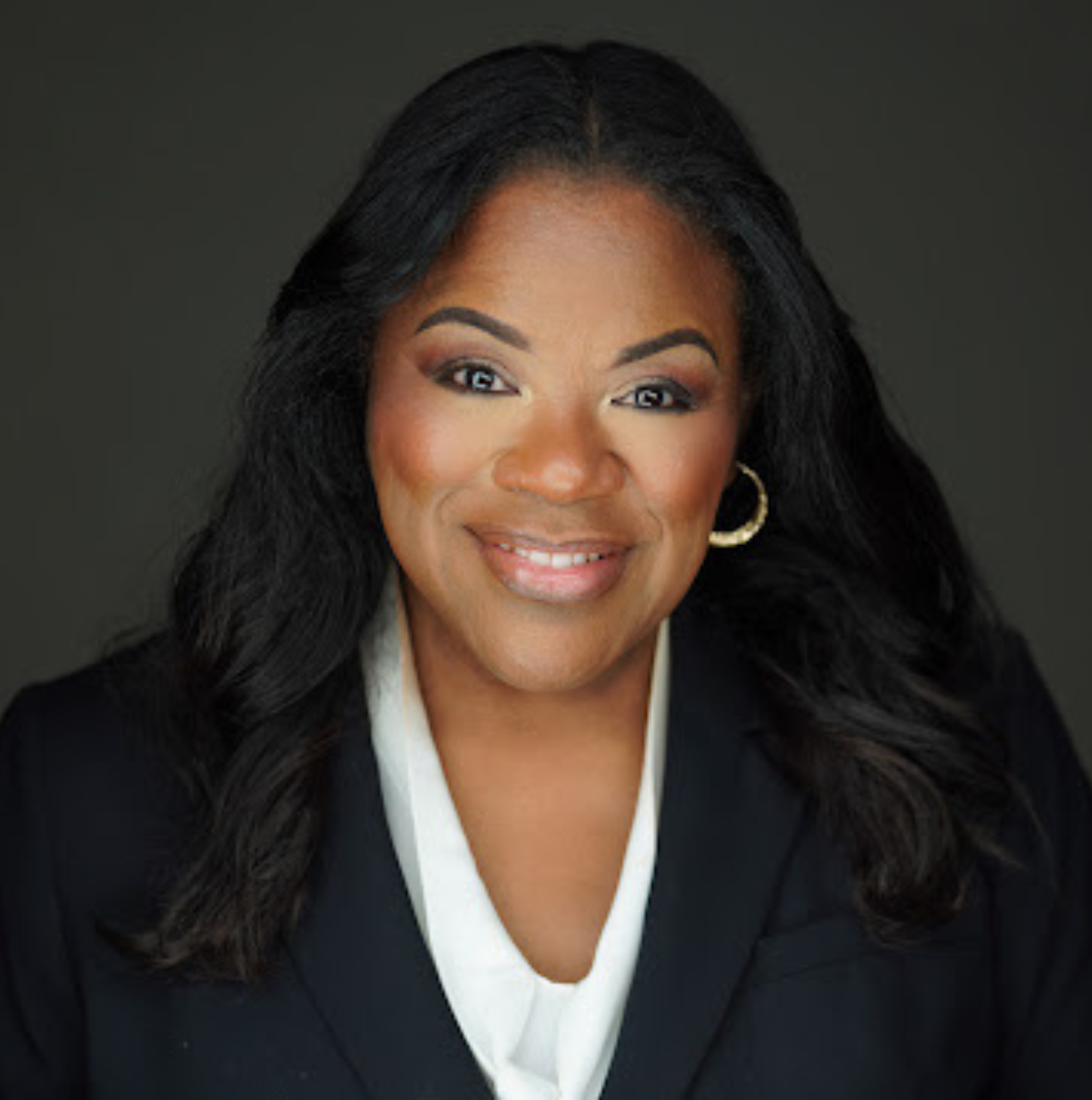 Lisa Wogwu in black blazer with white blouse against a dark background