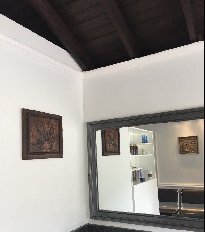 White-walled interior with a dark wood ceiling, large mirror, and framed wall art.
