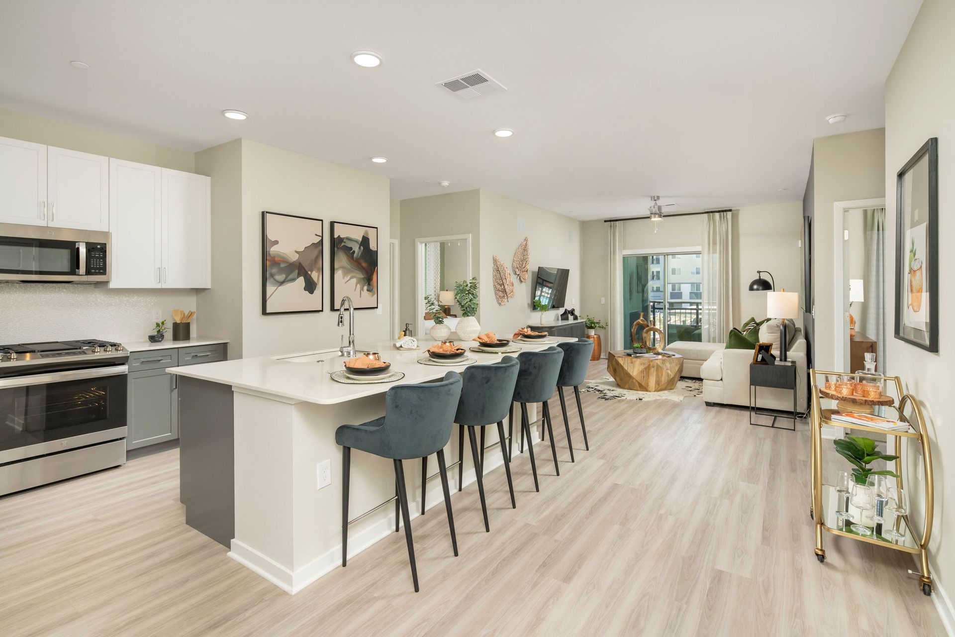 Open-concept apartment kitchen with island and bar seating, leading to a living area.