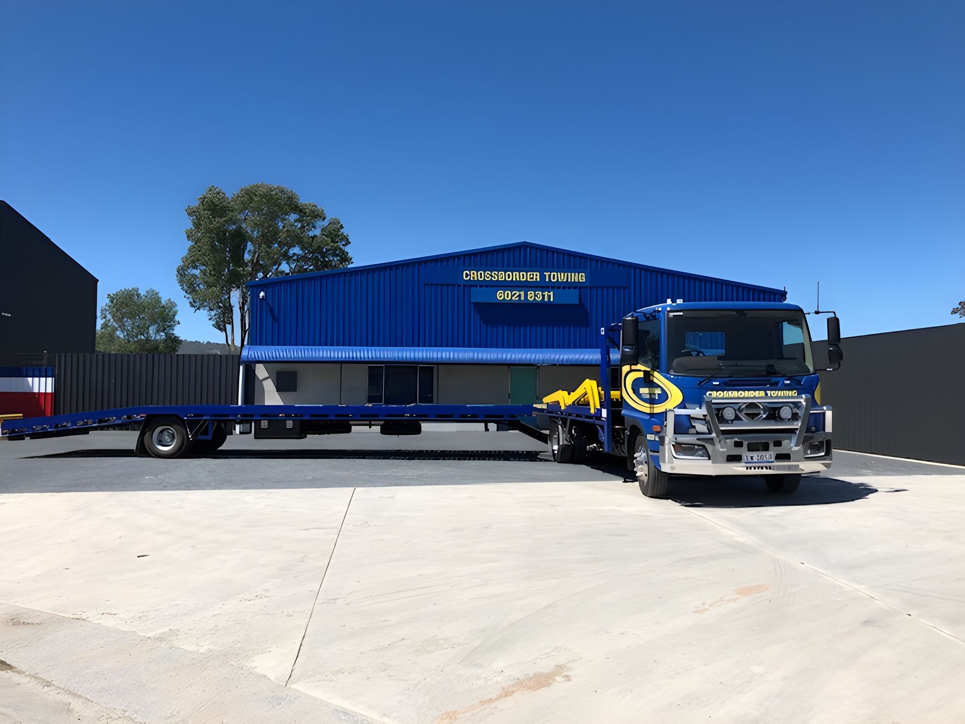 A blue tow truck parked in front of a blue building — Crossborder Towing in South Albury, NSW