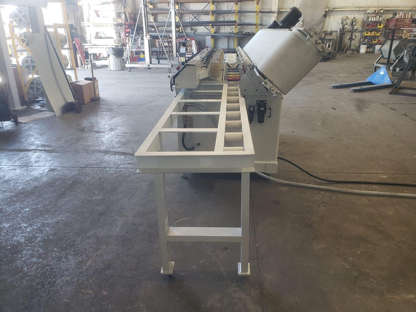 Metalworking machine in a shop; white table and equipment; concrete floor.