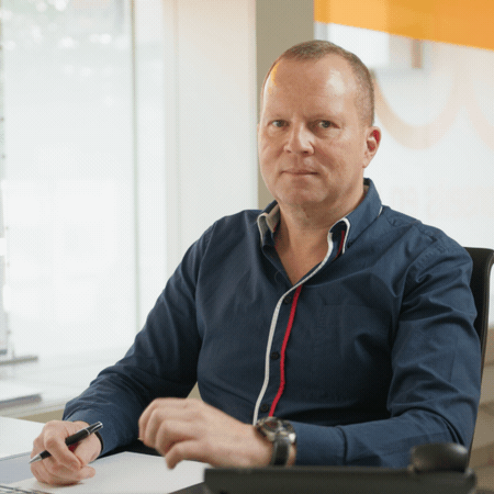 Un homme en chemise bleue est assis à un bureau avec un stylo à la main