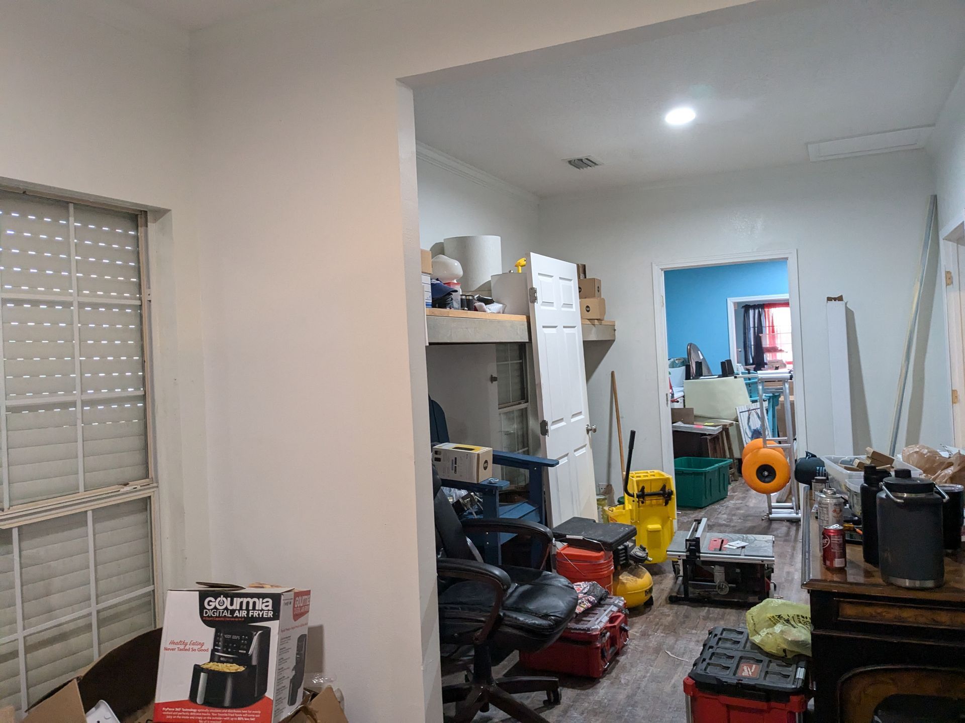 Hallway filled with cluttered furniture and construction materials; a window on left.