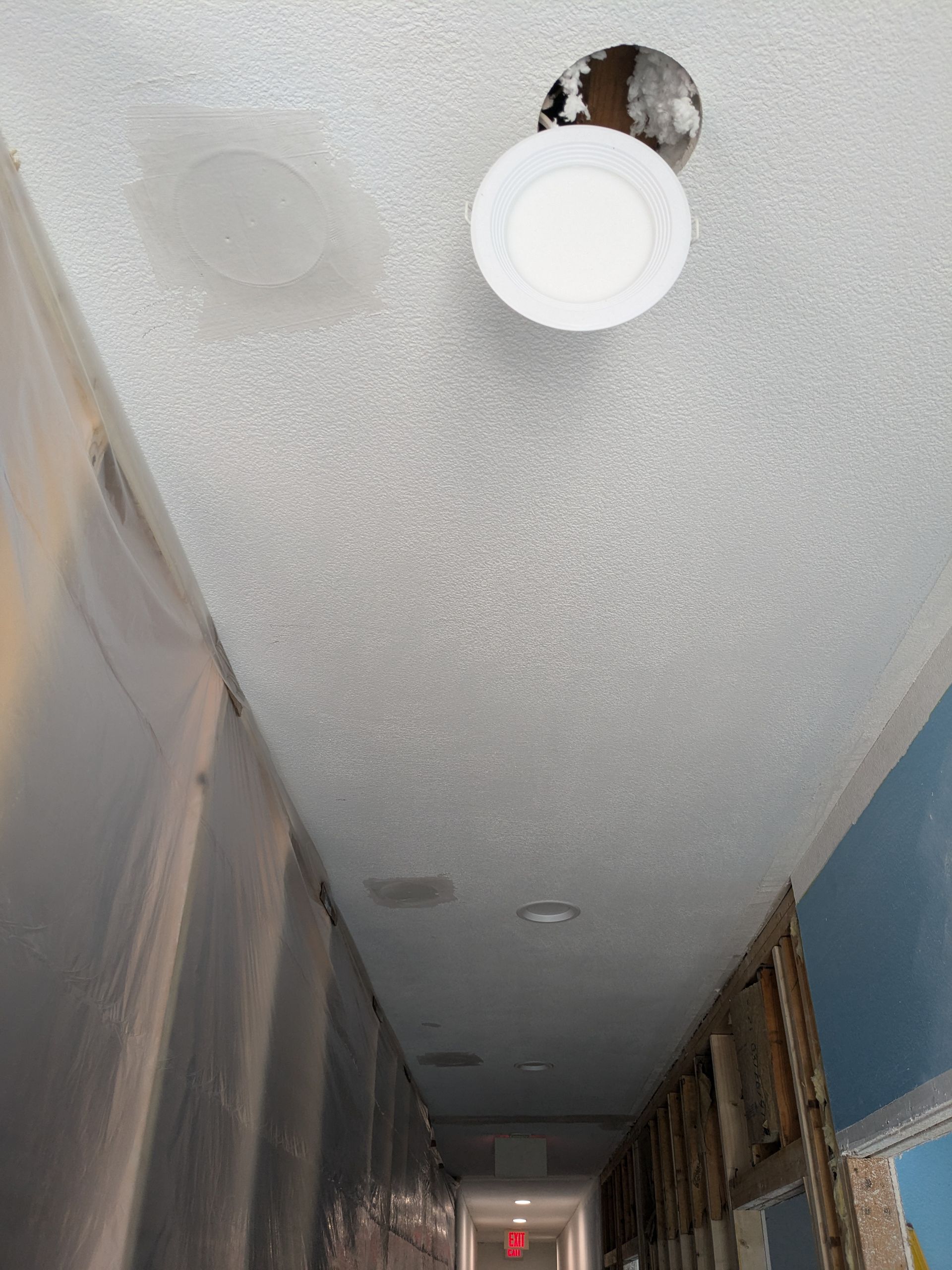 Hallway ceiling with water damage and a light fixture, with a plate catching water.