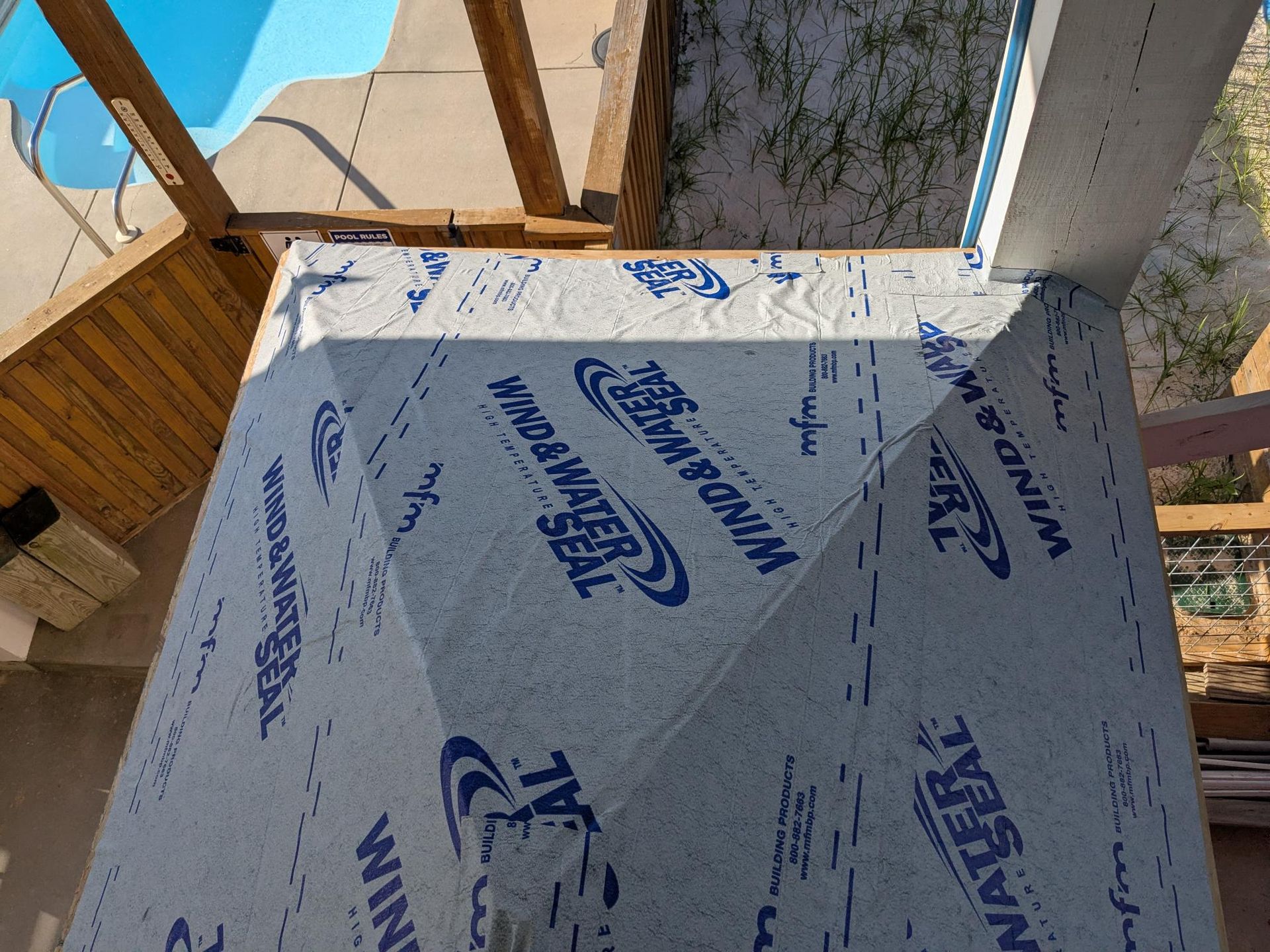Blue pool and wood beams above a covered area, covered in Wind & Water Seal material.