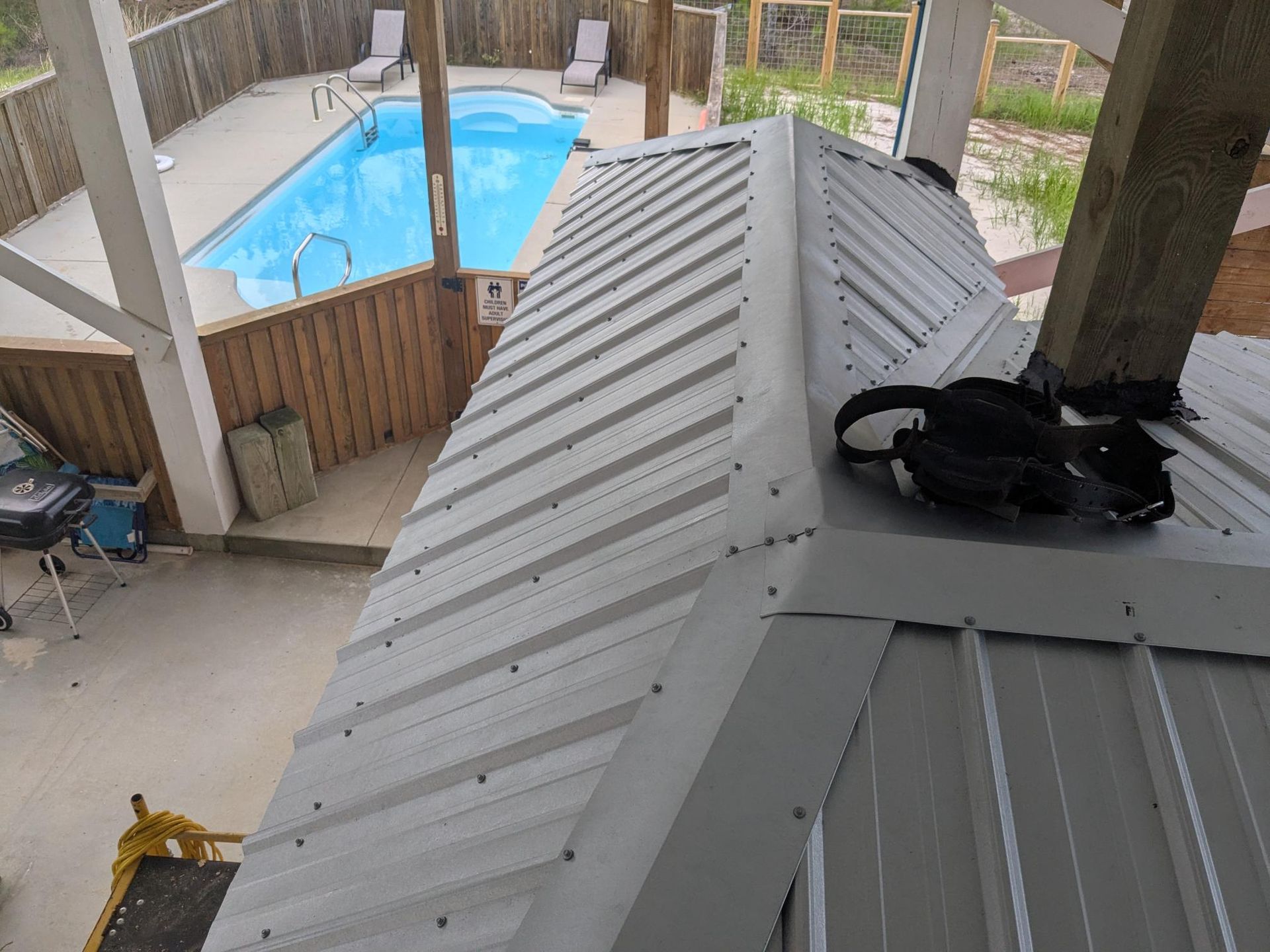 Gray metal roof with a swimming pool visible in the background.