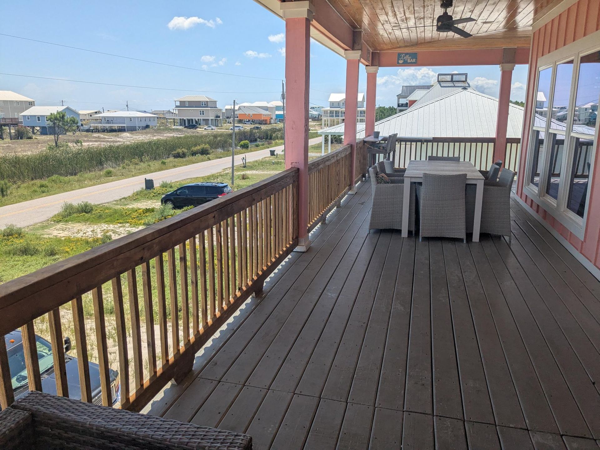 Deck with outdoor dining table, overlooking a coastal neighborhood.