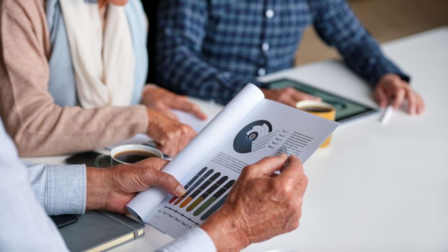 Hands reviewing a printed chart and graphs at a meeting table