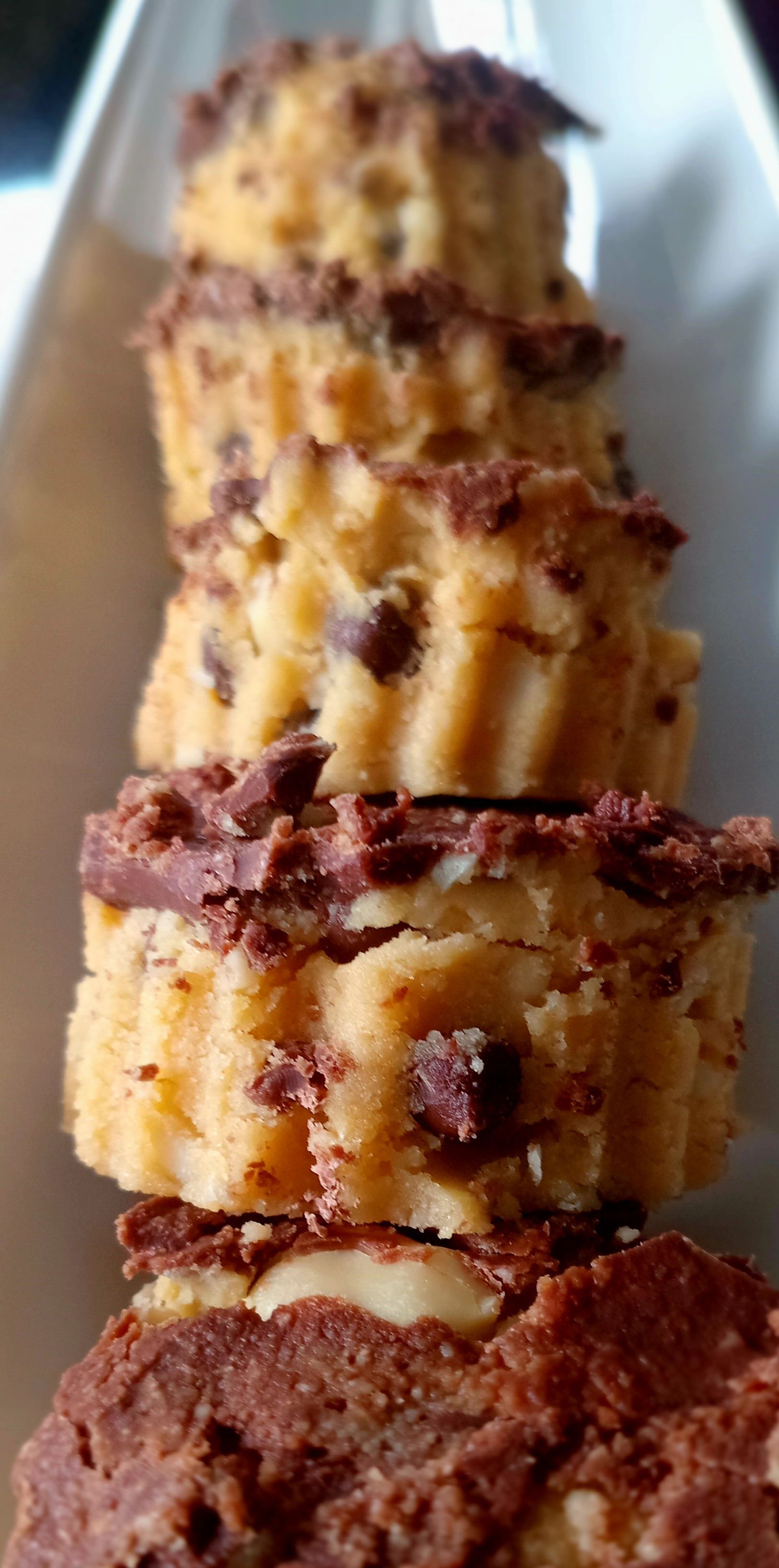 Stack of small, golden baked goods with dark chocolate chips on top.