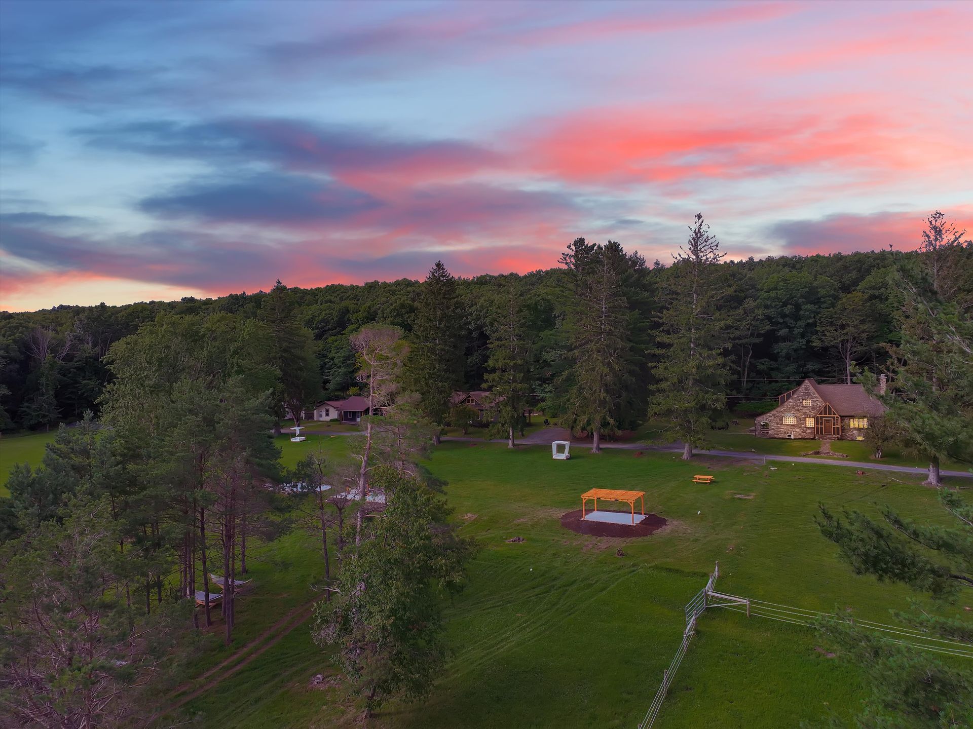 Drone view at sunset over the lawn, pergola and forest