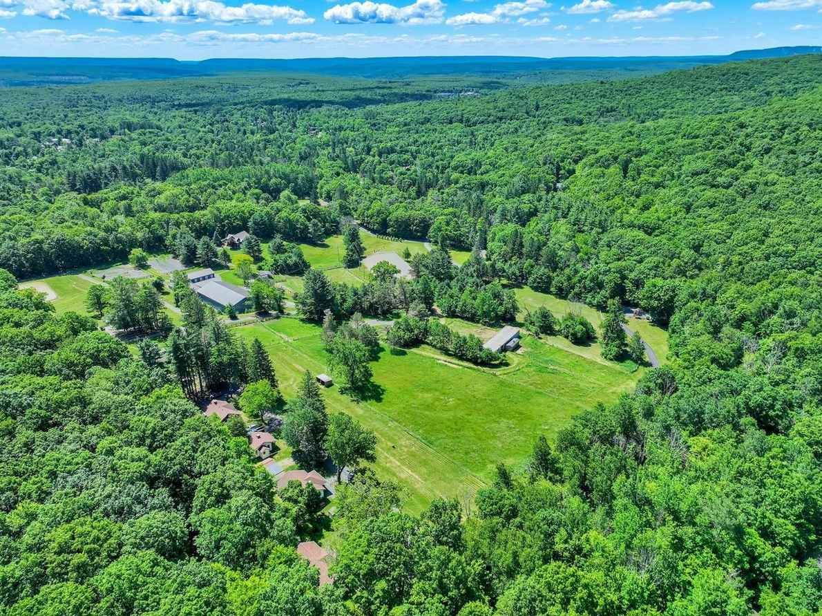 Aerial view of the Ik & Lo Resort houses and lawns surrounded by green summer forest in the Poconos