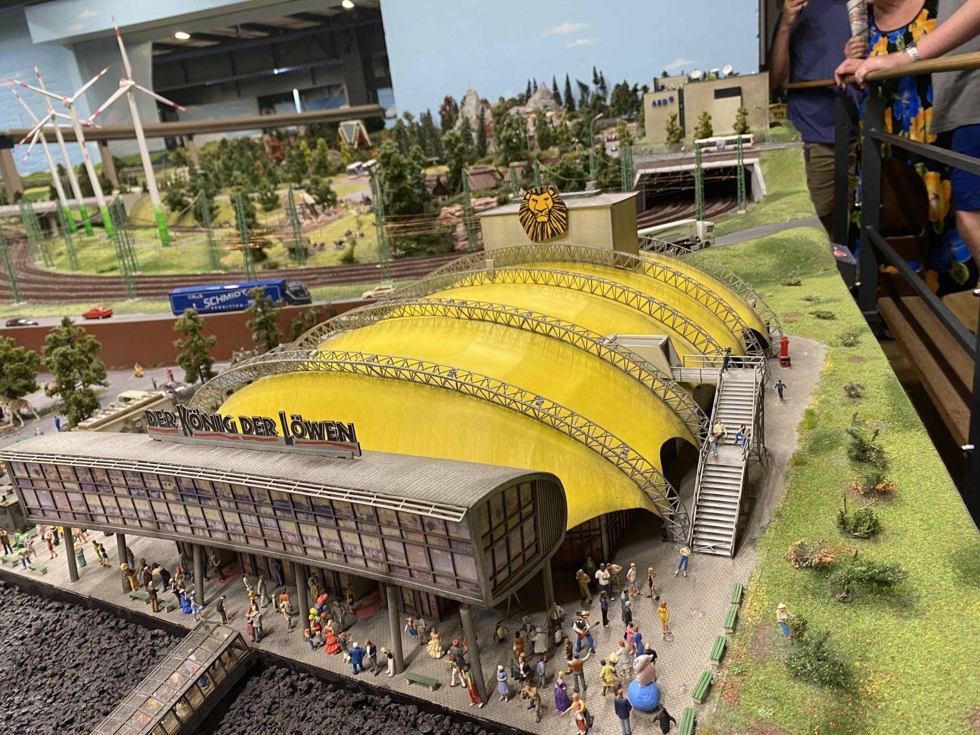 Miniatur-Stadtszene mit gelbem Kuppelgebäude, Zug und Figuren.