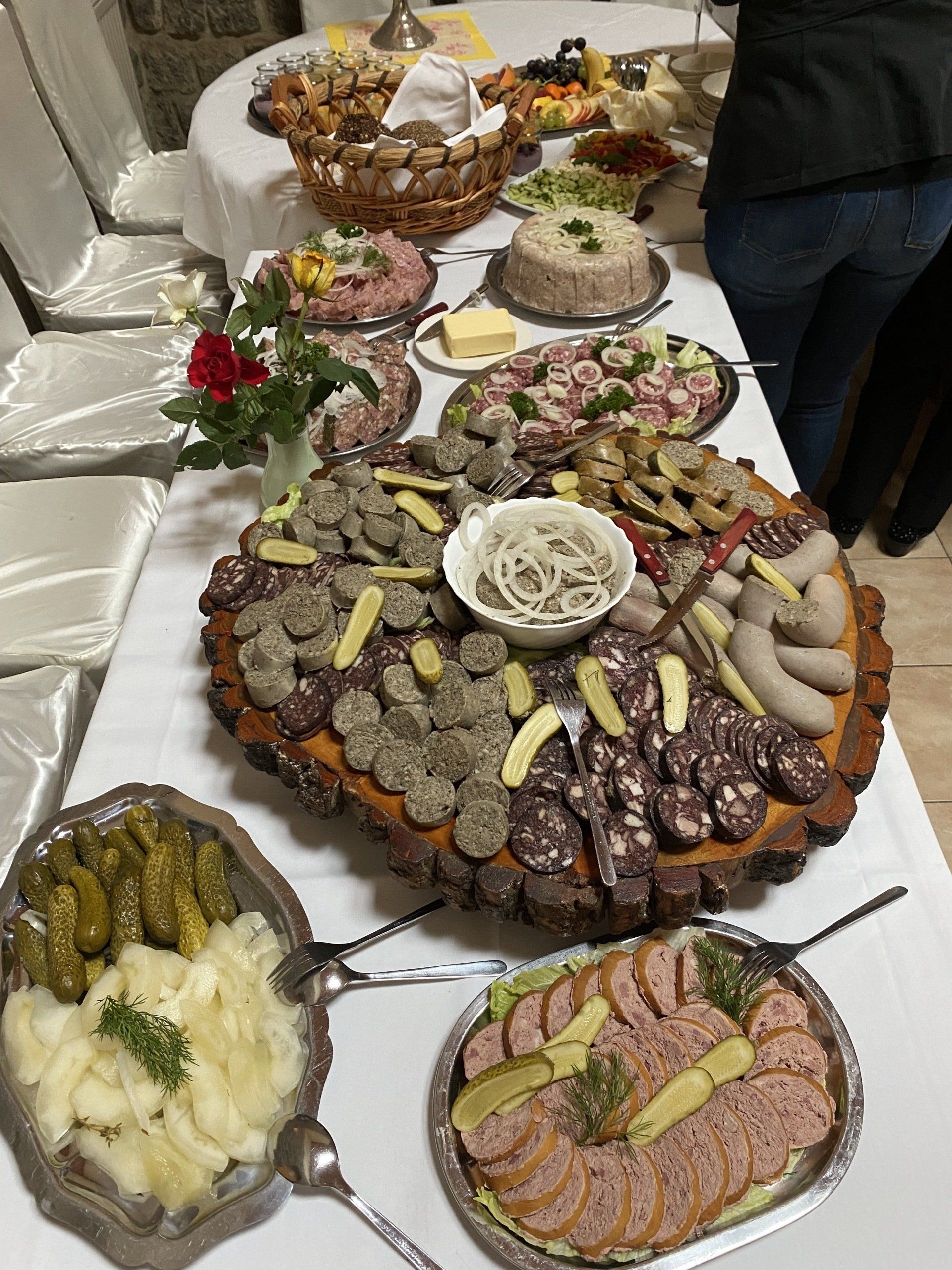 Buffettisch mit vielen Speisen: Fleisch, Käse, eingelegtes Gemüse, Salate. Weiße Tischdecke, Innenbereich.