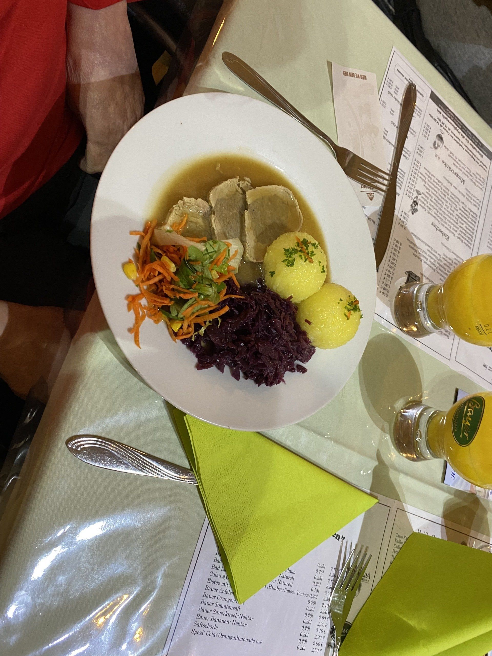 Teller mit deutschem Essen: Fleisch in Soße, Kartoffeln, Rotkohl und Karotten auf einem weißen Teller.