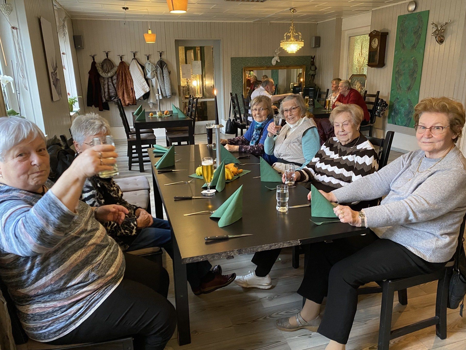 Eine Gruppe von Menschen sitzt an einem Restauranttisch und stößt mit Getränken an.