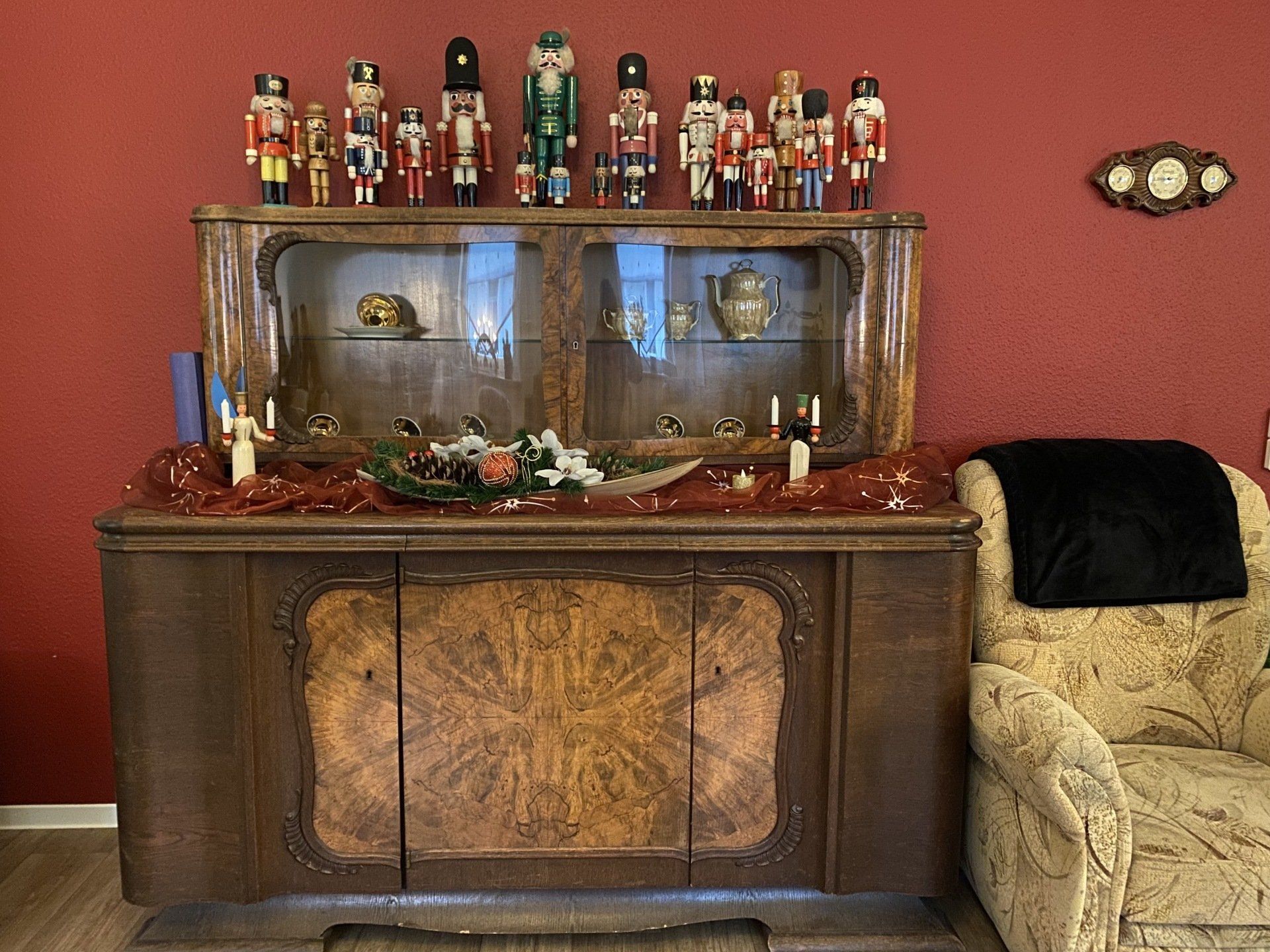 Holzschrank mit Nussknackern oben drauf, Weihnachtsdekor, rote Wand und floraler Akzent.