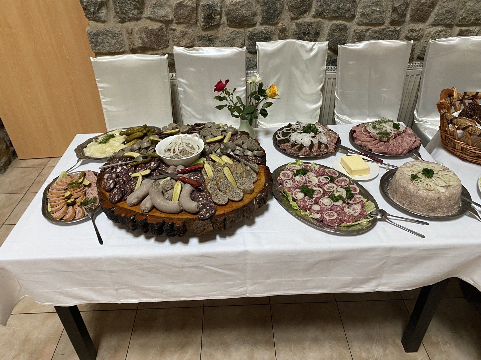 Ein mit verschiedenen Fleischsorten und Gerichten beladener Tisch, der an einer Steinwand steht, wahrscheinlich ein Buffet.