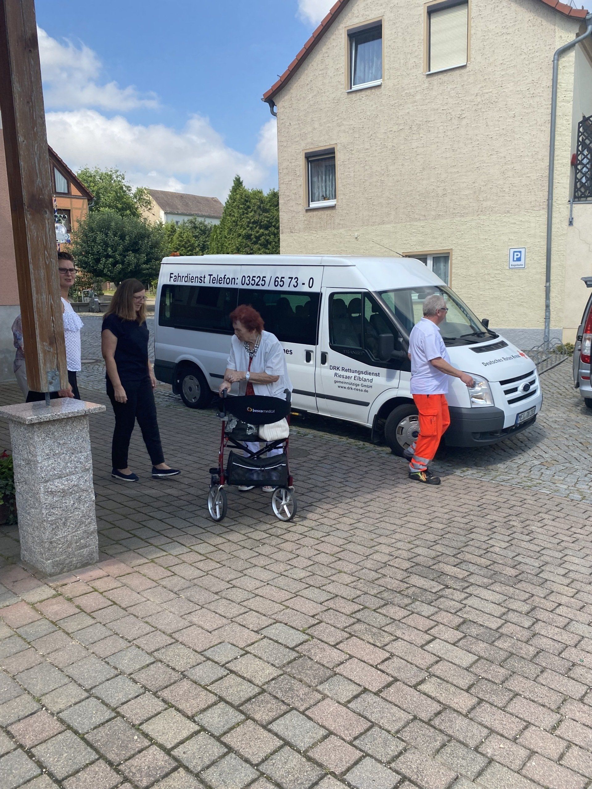 Menschen in der Nähe eines weißen Lieferwagens, einer mit einem Rollator. 