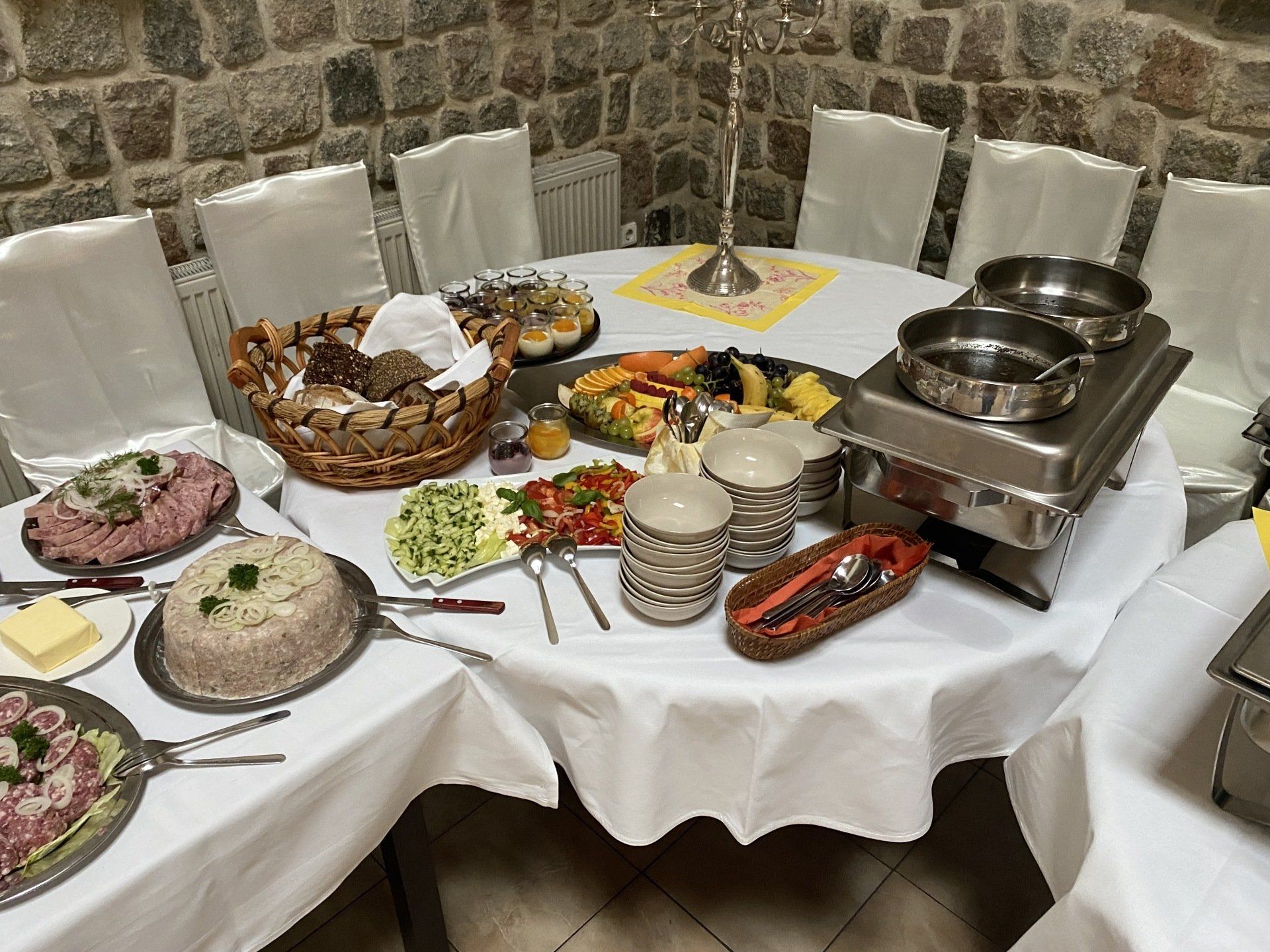 Buffettisch mit Speisen beladen: Salate, Brot, Fleisch und warme Gerichte, gedeckt für eine Zusammenkunft.