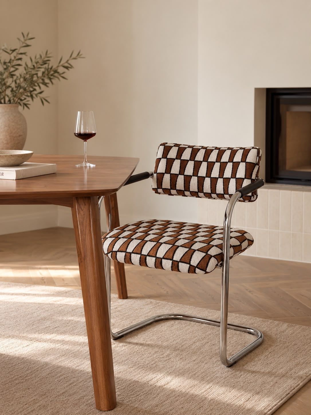 Moderne stoel bij een houten tafel in een zonnige, minimalistische eetkamer, met een wijnglas en een vaas op tafel