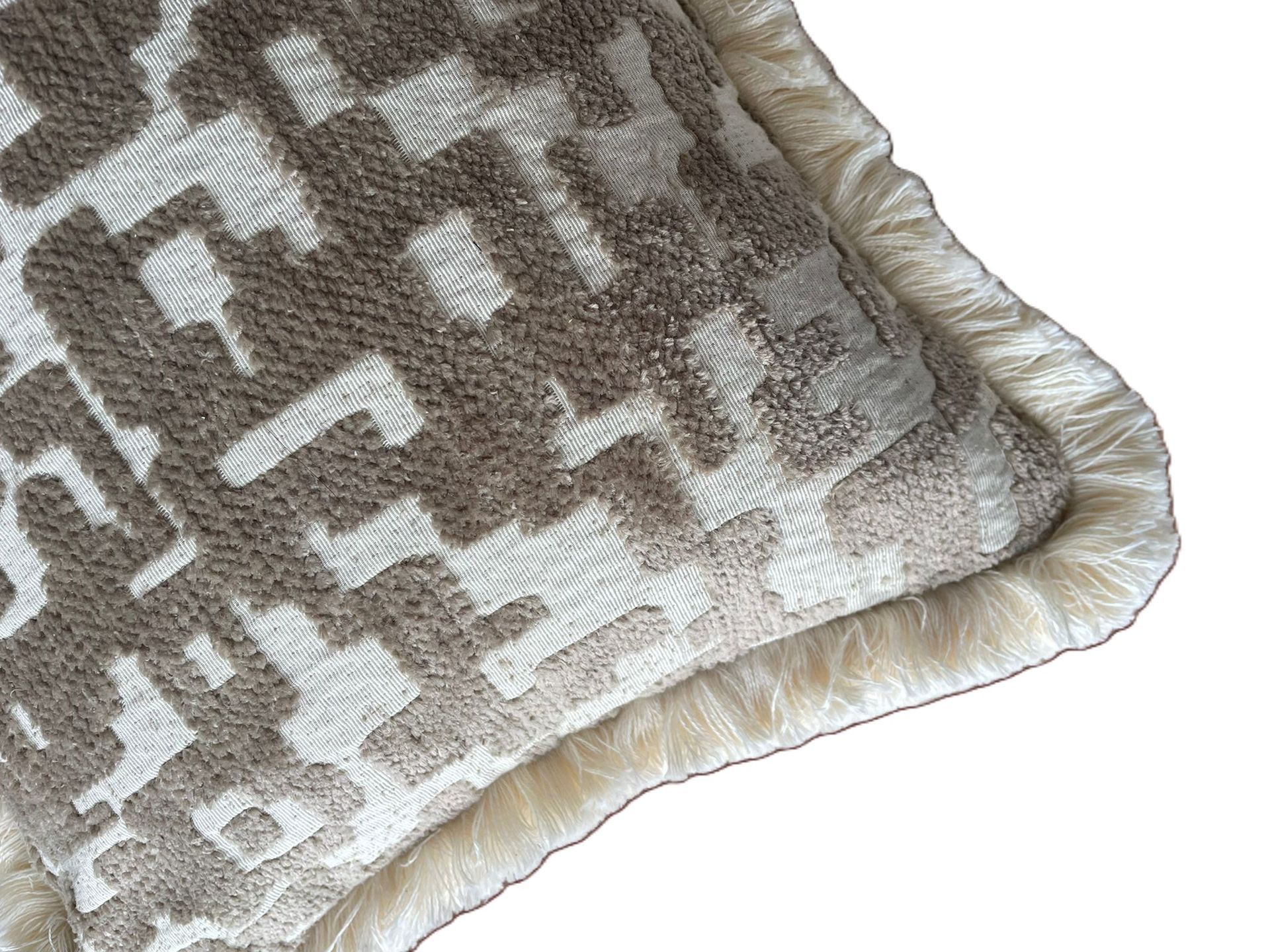 Rechthoekig decoratief kussen met beige- en grijs patroon op een witte achtergrond.