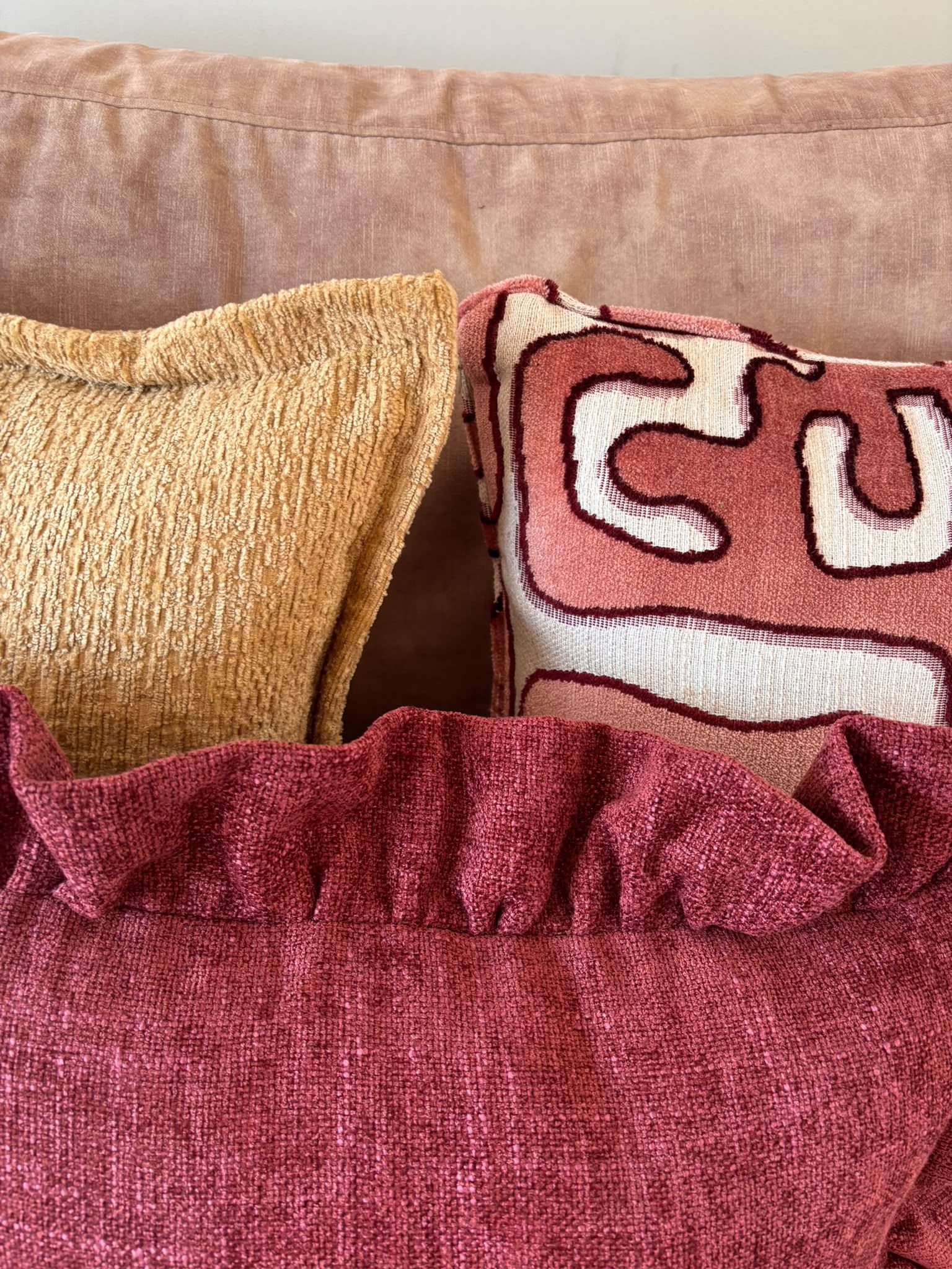 Diverse sierkussens in beige, bordeauxrood en gestreepte patronen op een witte achtergrond