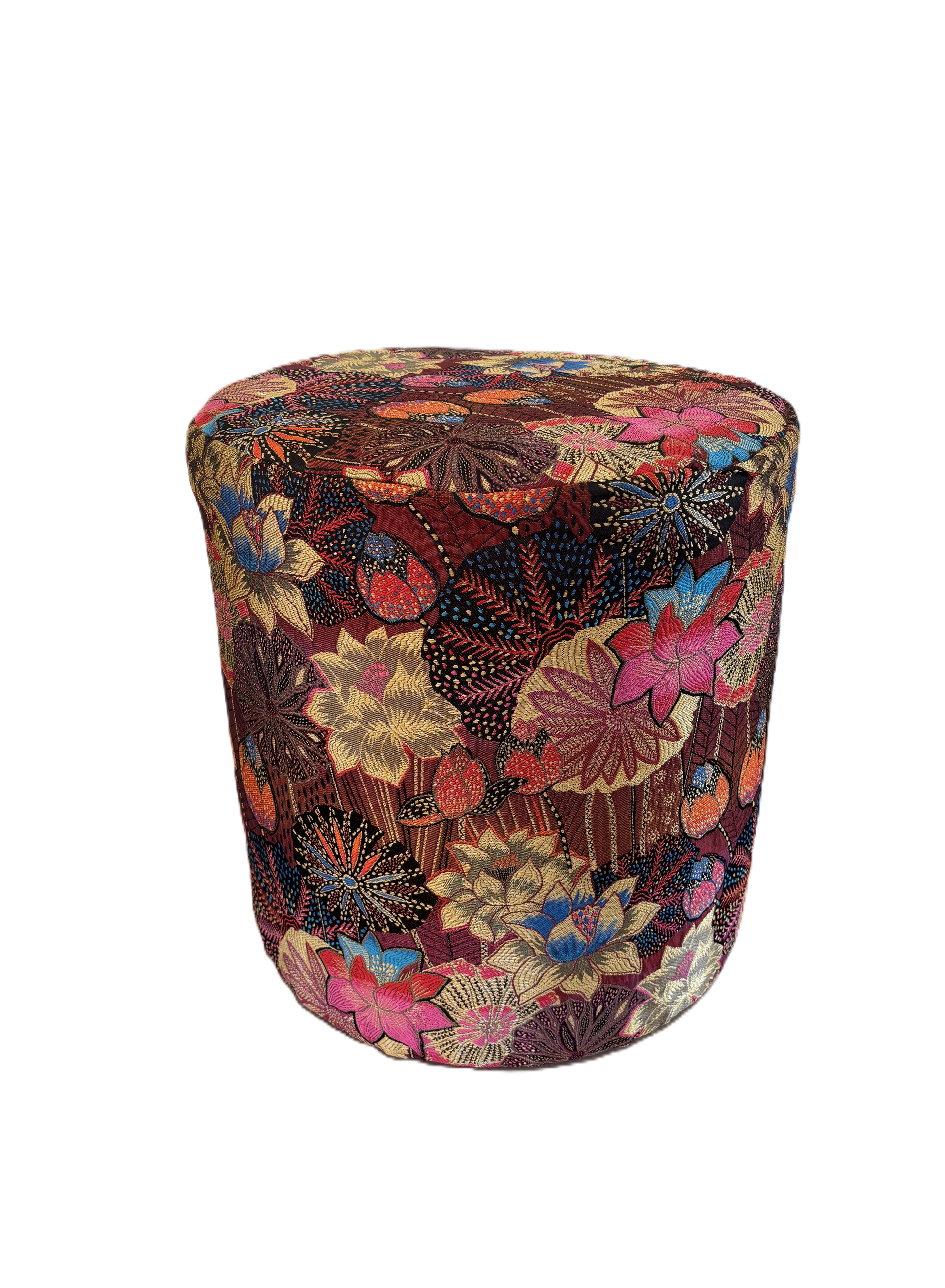 Kleurrijke poef met bloemenprint naast een zwarte open haard in een woonkamer.