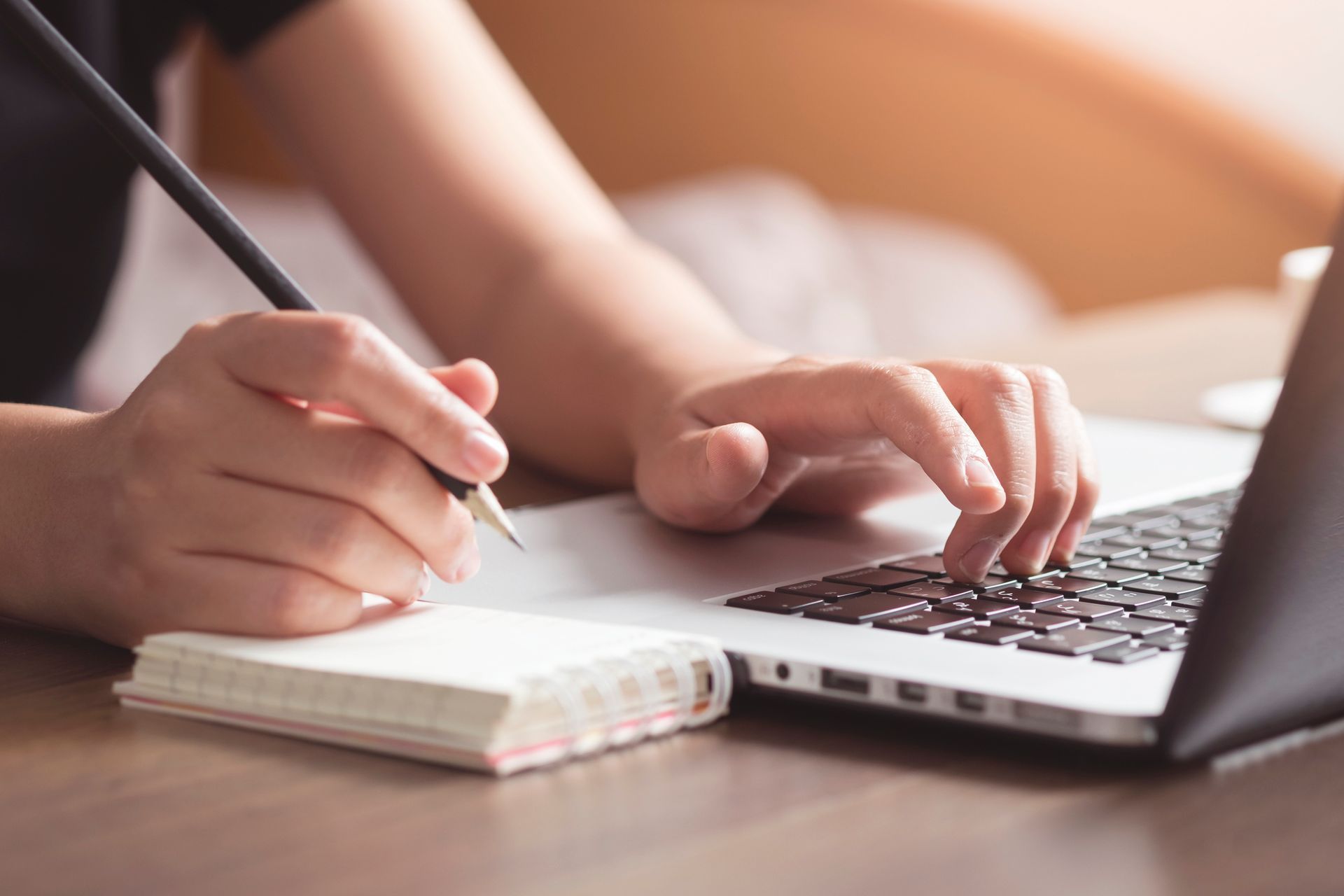 Writing in a Notebook While Typing on a Laptop