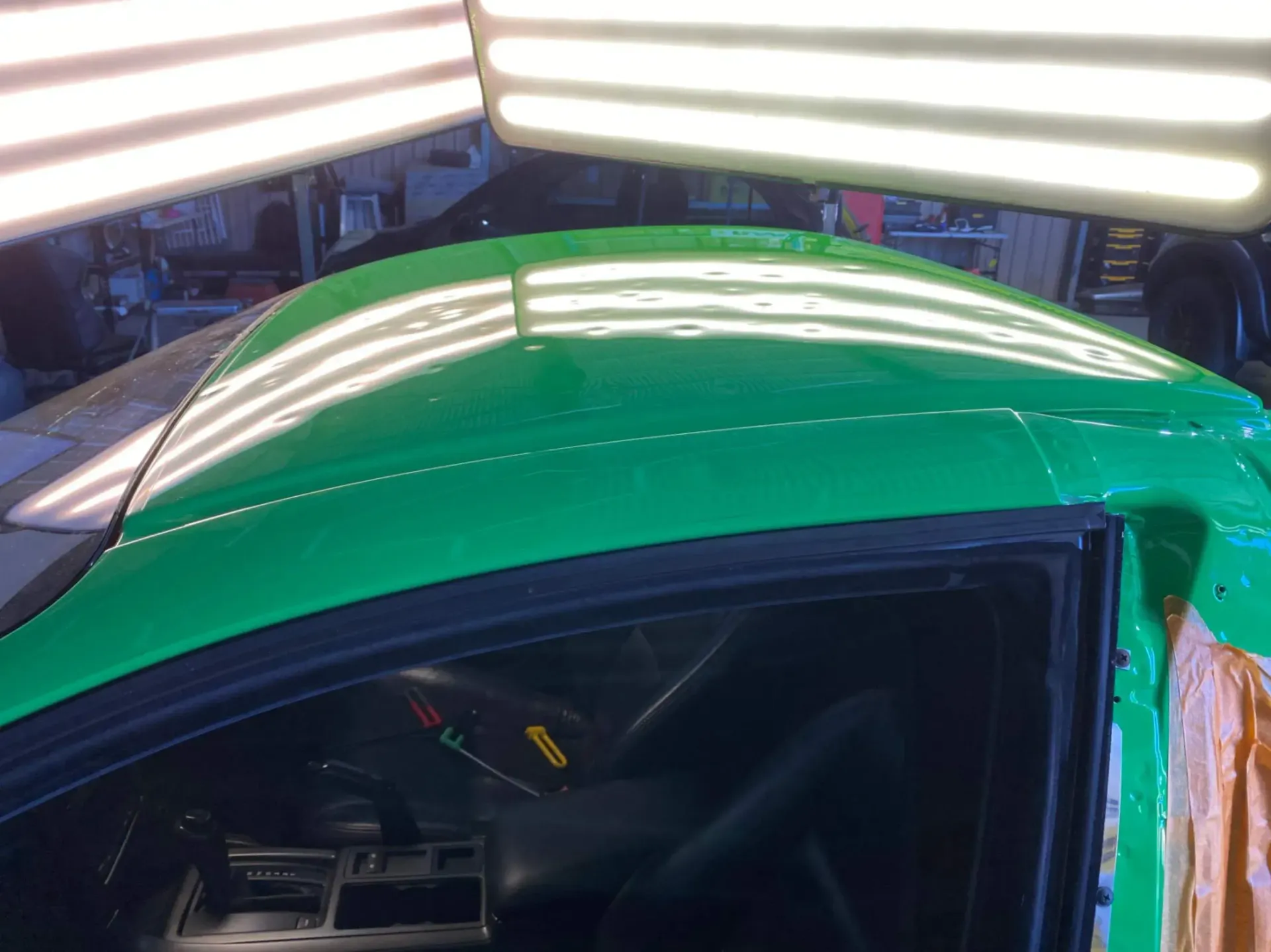 The roof of a green car is dents repaired in a garage.